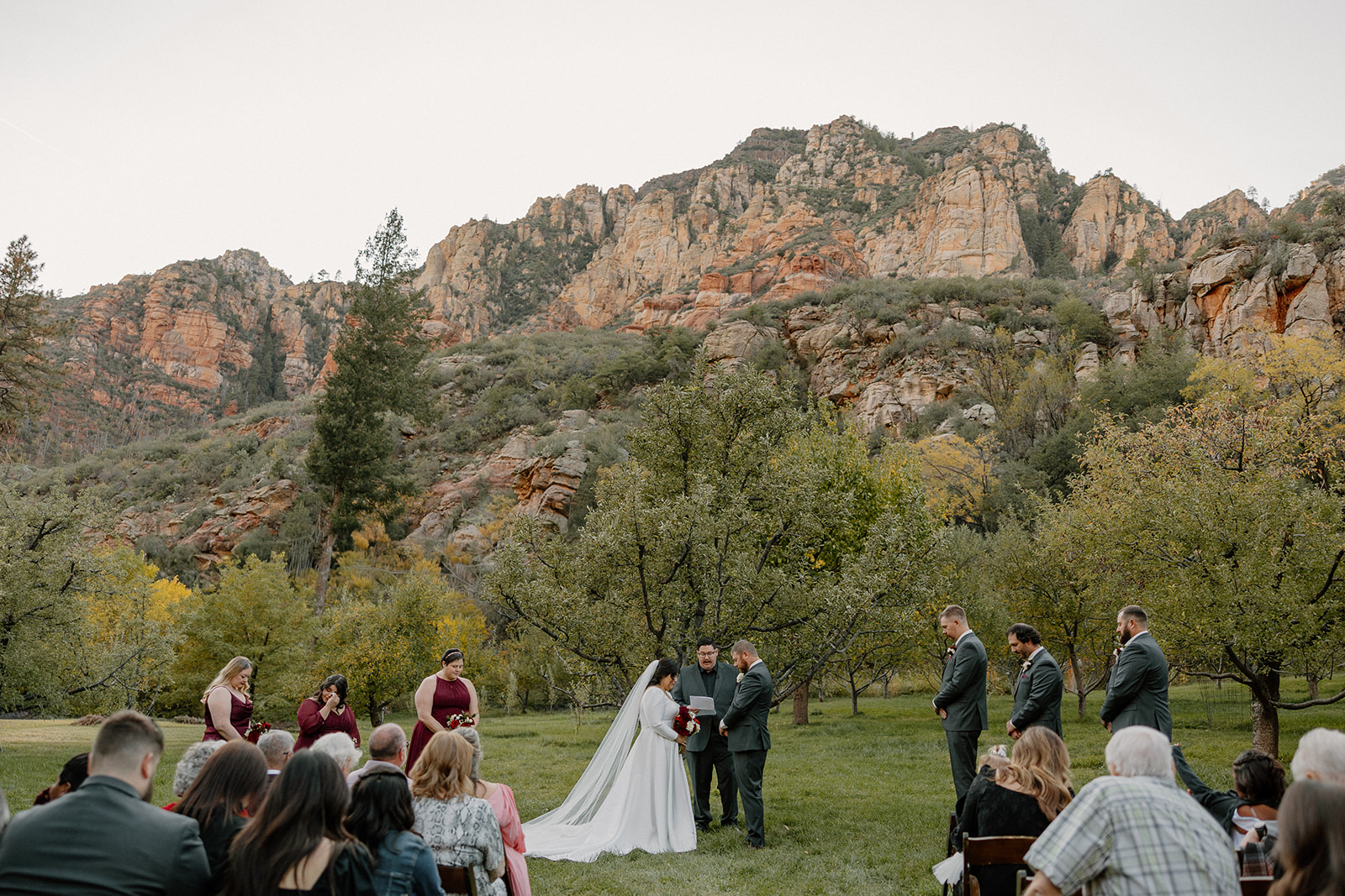 Outdoor wedding ceremony at a Sedona wedding venue with guests seated beneath red rock cliffs