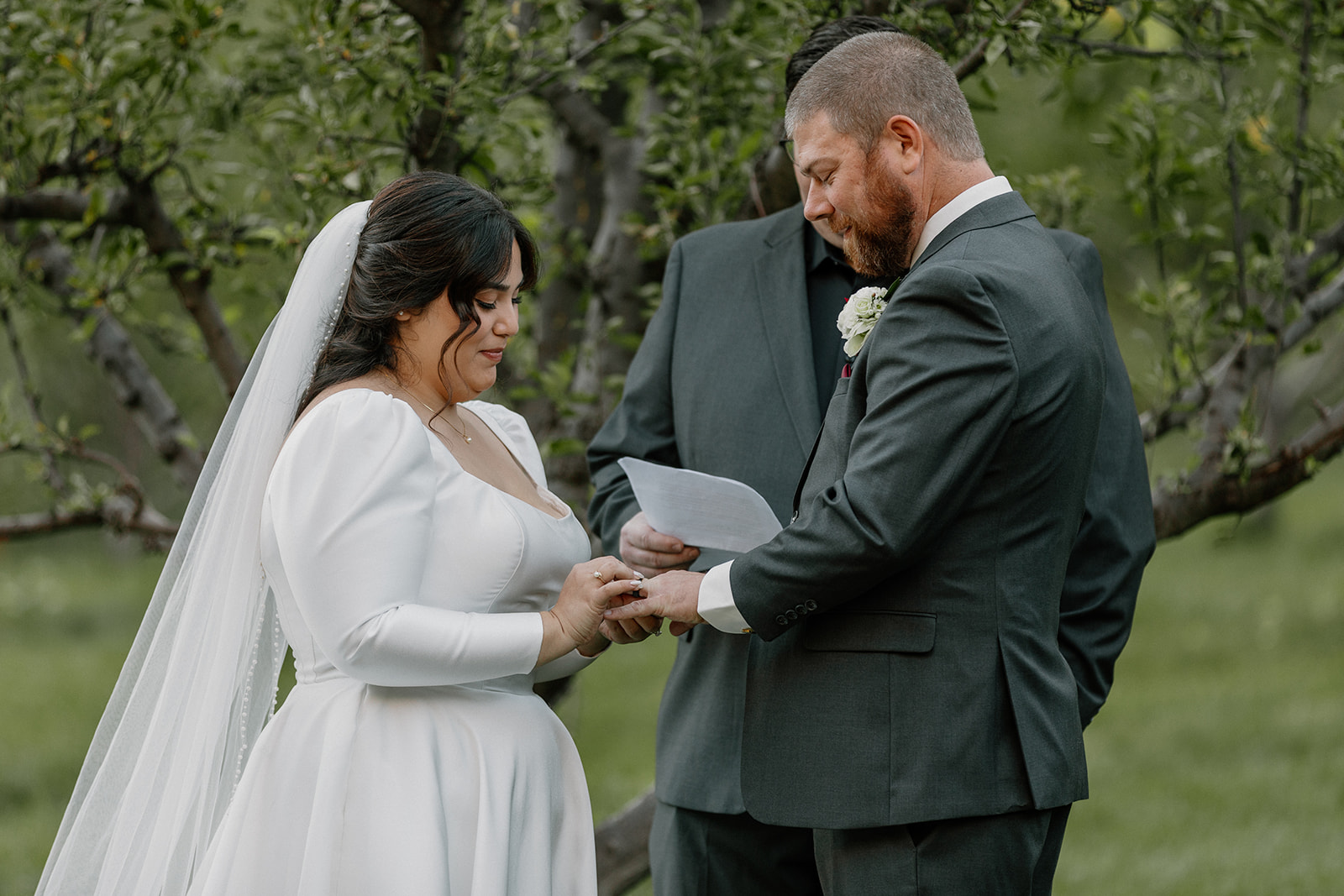 Bride placing a wedding ring on the groom’s finger during an outdoor ceremony at Orchard Canyon on Oak Creek