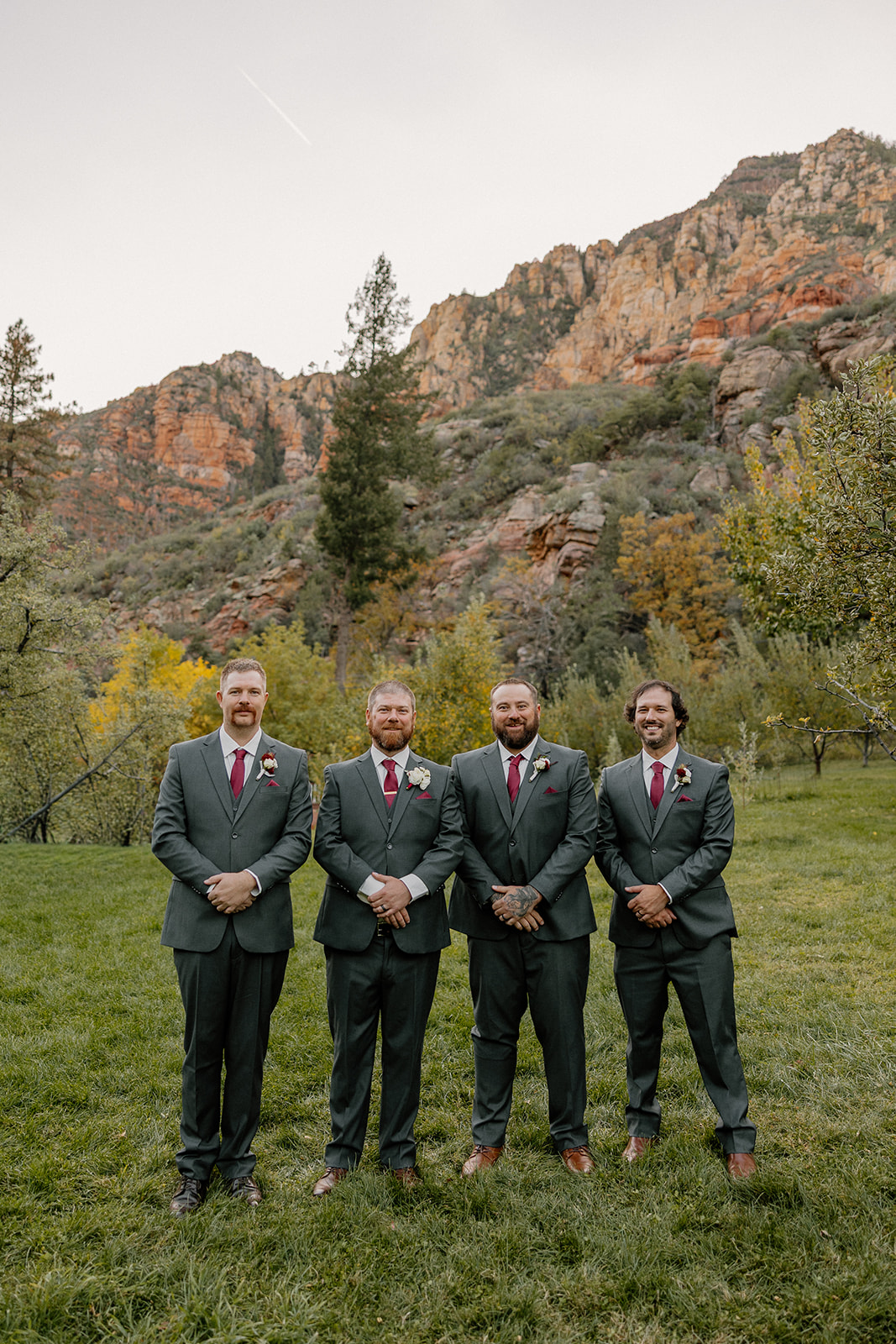 Groomsmen standing together in a grassy field with red rock views in Sedona