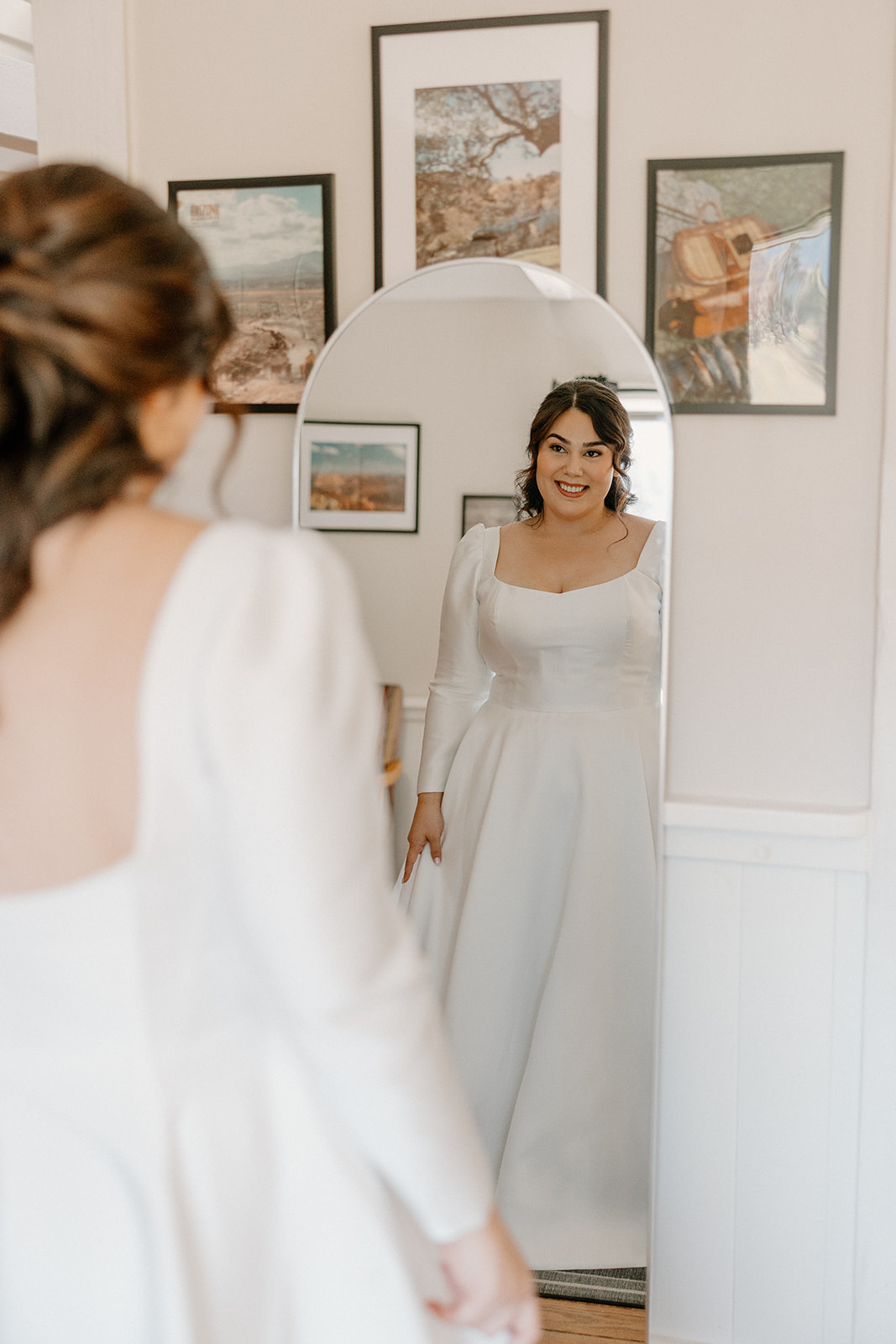 Bride smiling at her reflection while getting ready indoors before the ceremony