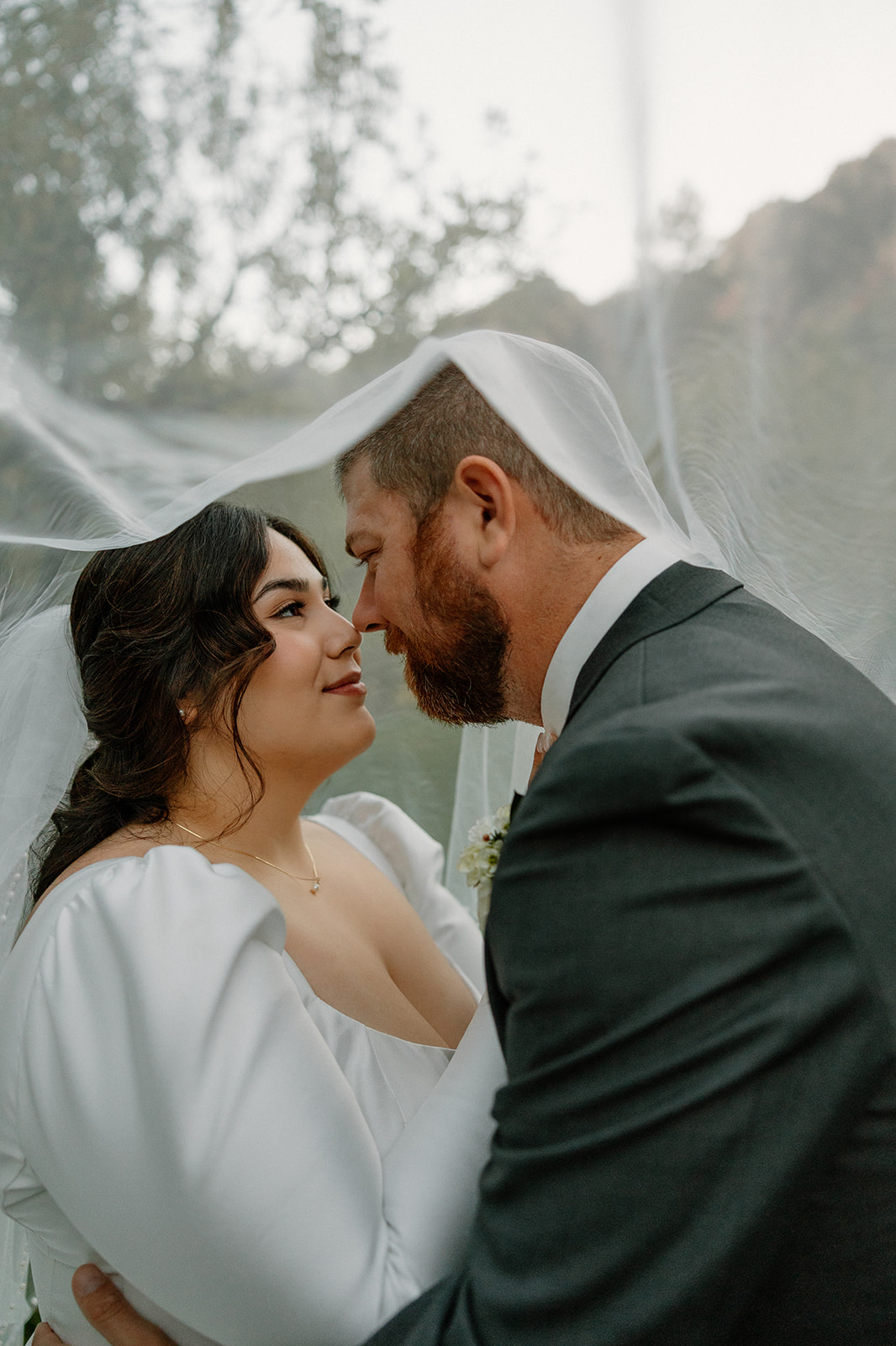 Romantic portrait of the bride and groom under the veil surrounded by trees at Orchard Canyon on Oak Creek