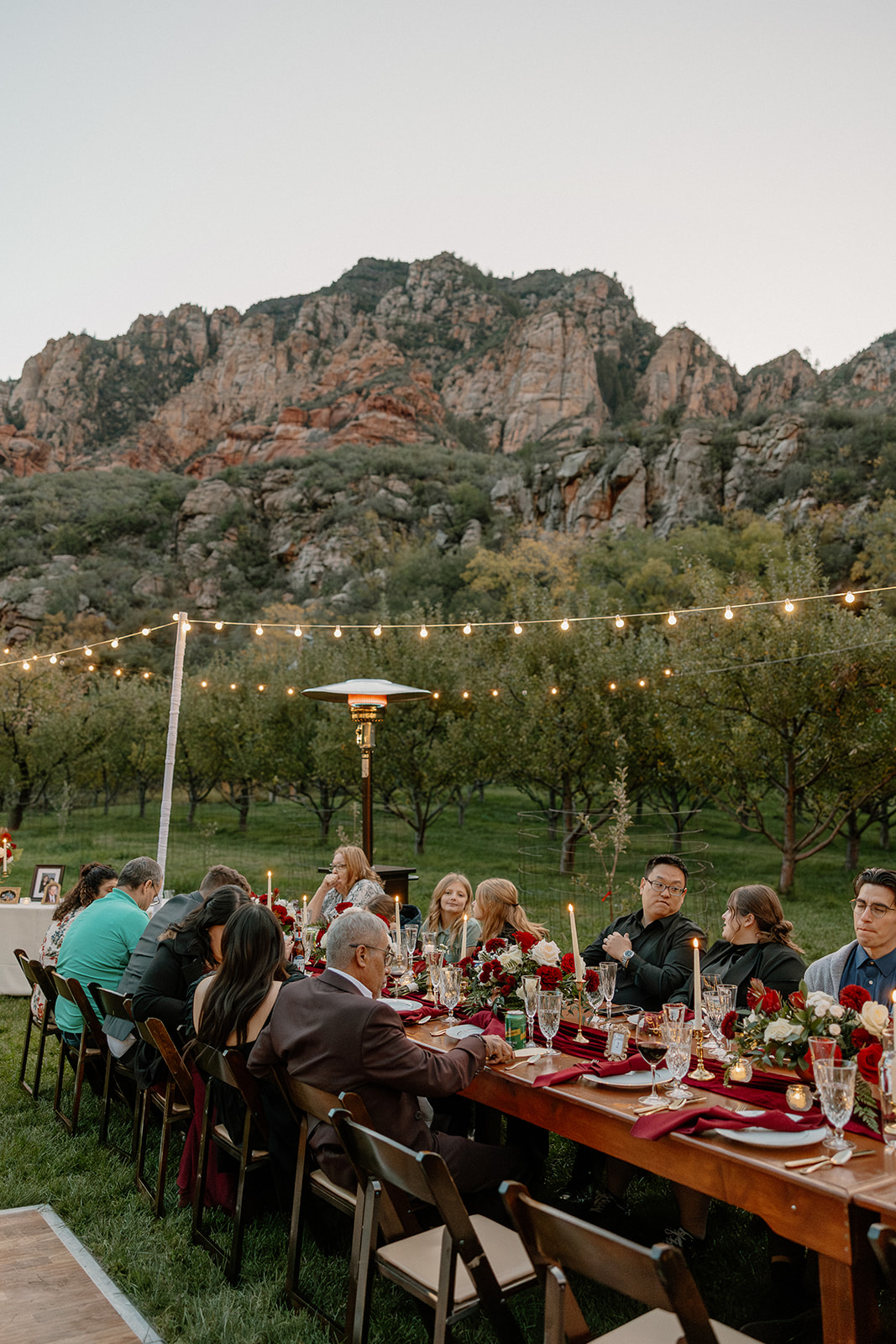 Long dinner table set outdoors at a Sedona wedding venue with mountain views and string lights