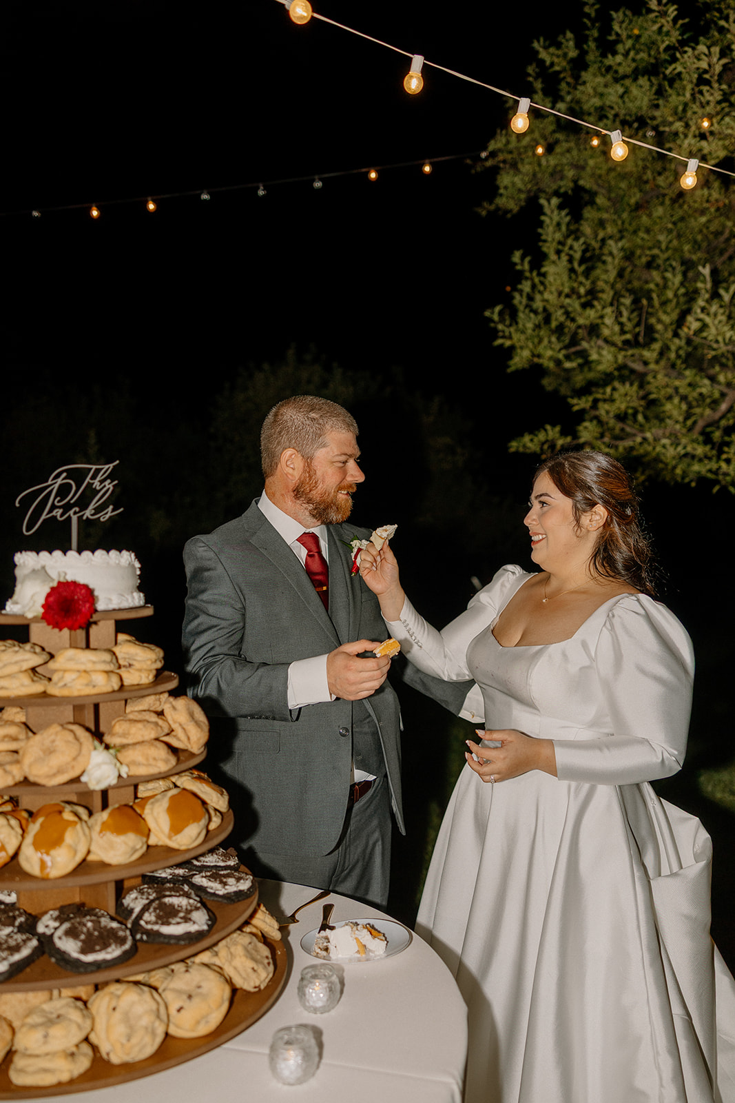 Bride and groom laughing while sharing dessert at a Sedona wedding venue under string lights