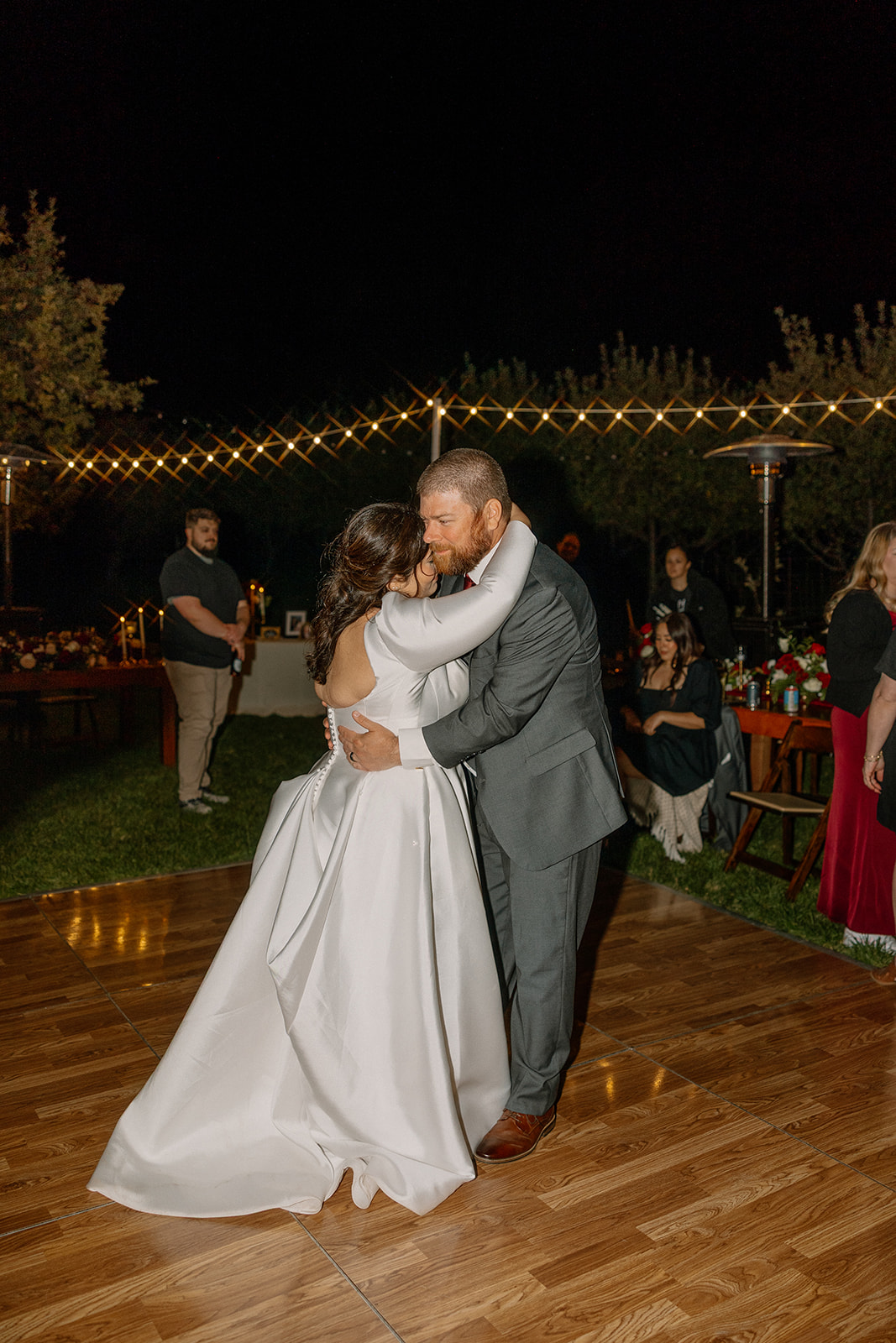 Bride and groom dancing together on a wooden dance floor under string lights at a Sedona wedding venue