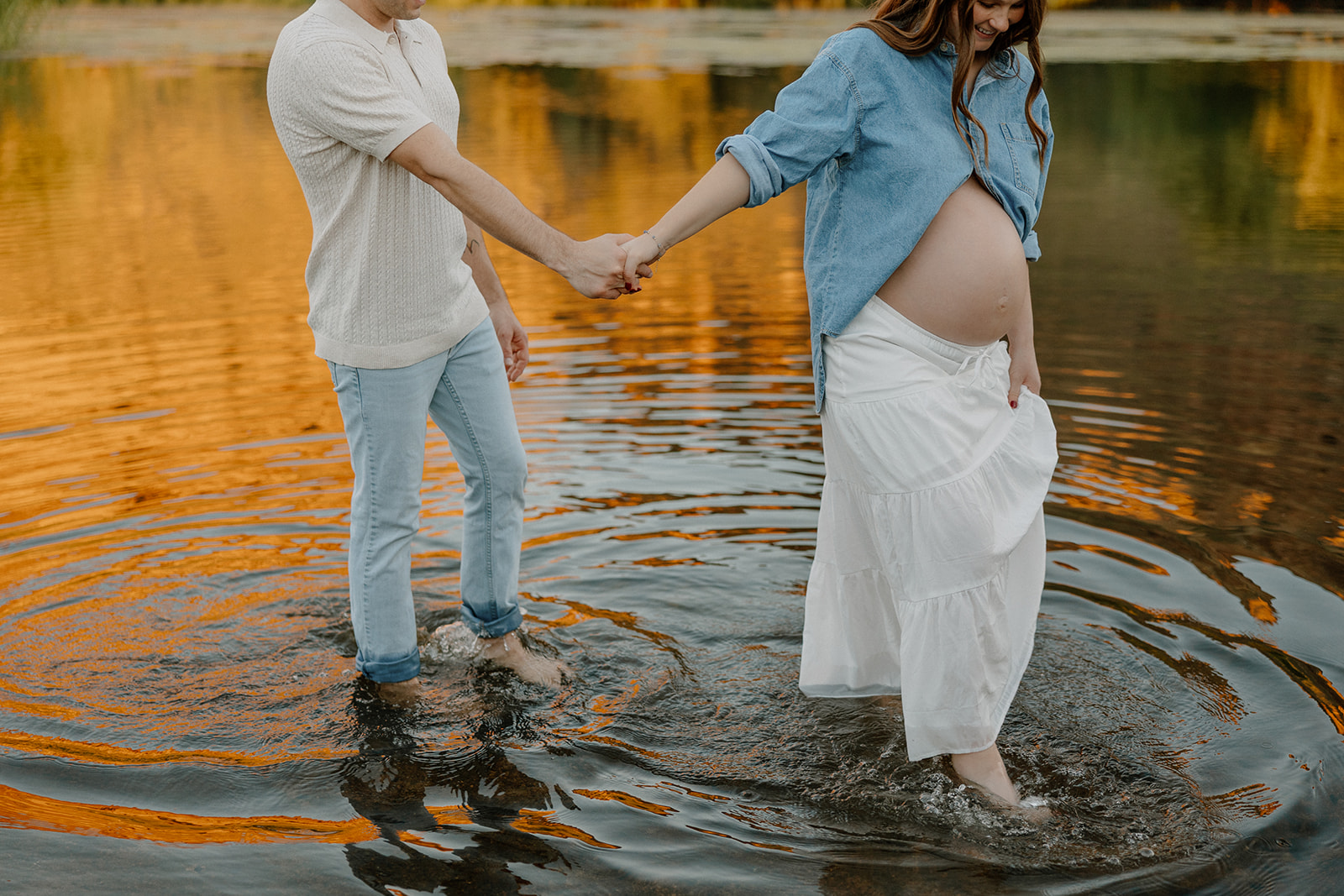 Couple holding hands and walking through the water during a relaxed maternity session in Arizona
