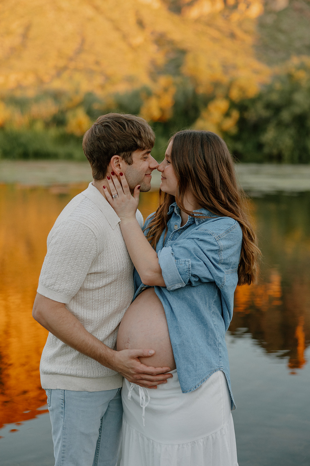 Couple facing each other and smiling with soft sunset light reflecting off the river
