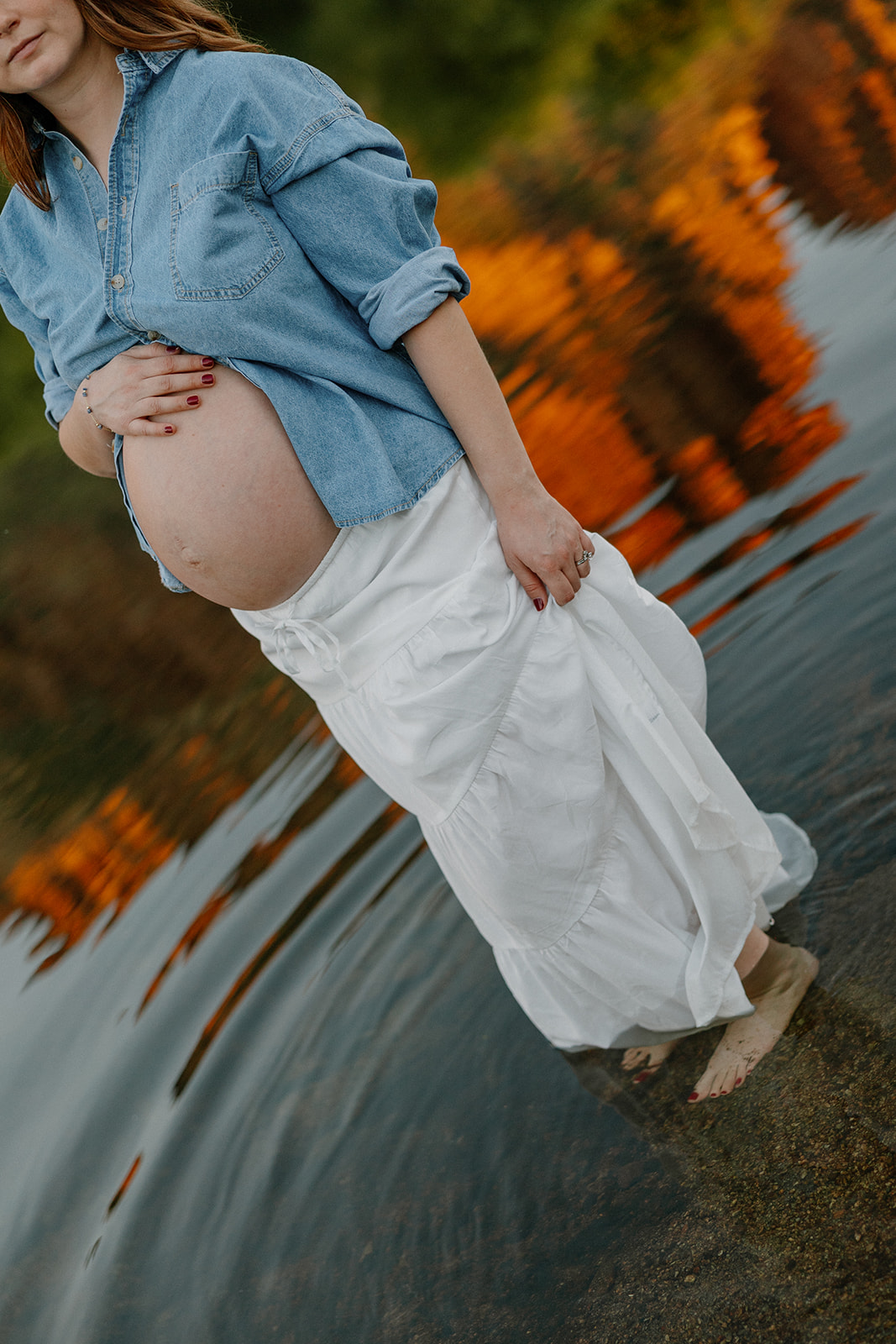 Detail of baby bump and flowing white skirt in shallow river water during golden hour maternity photos, Arizona maternity photographer

