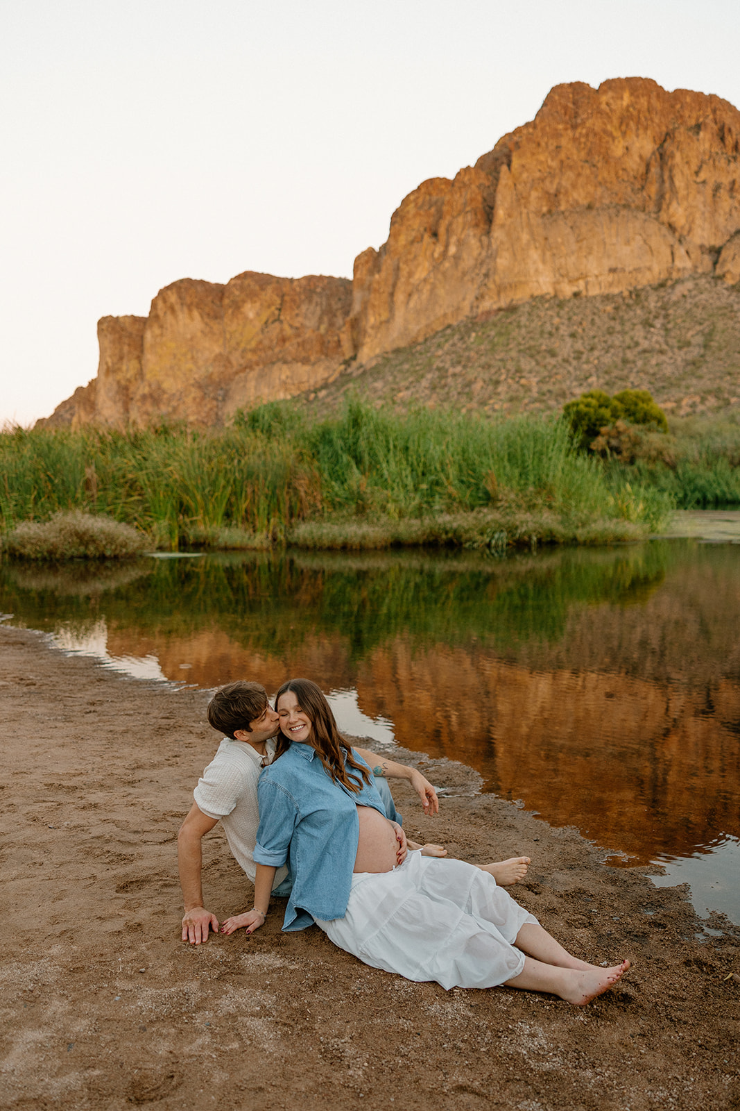 Couple sitting together on the river’s edge at sunset during maternity photos, Arizona maternity photographer
