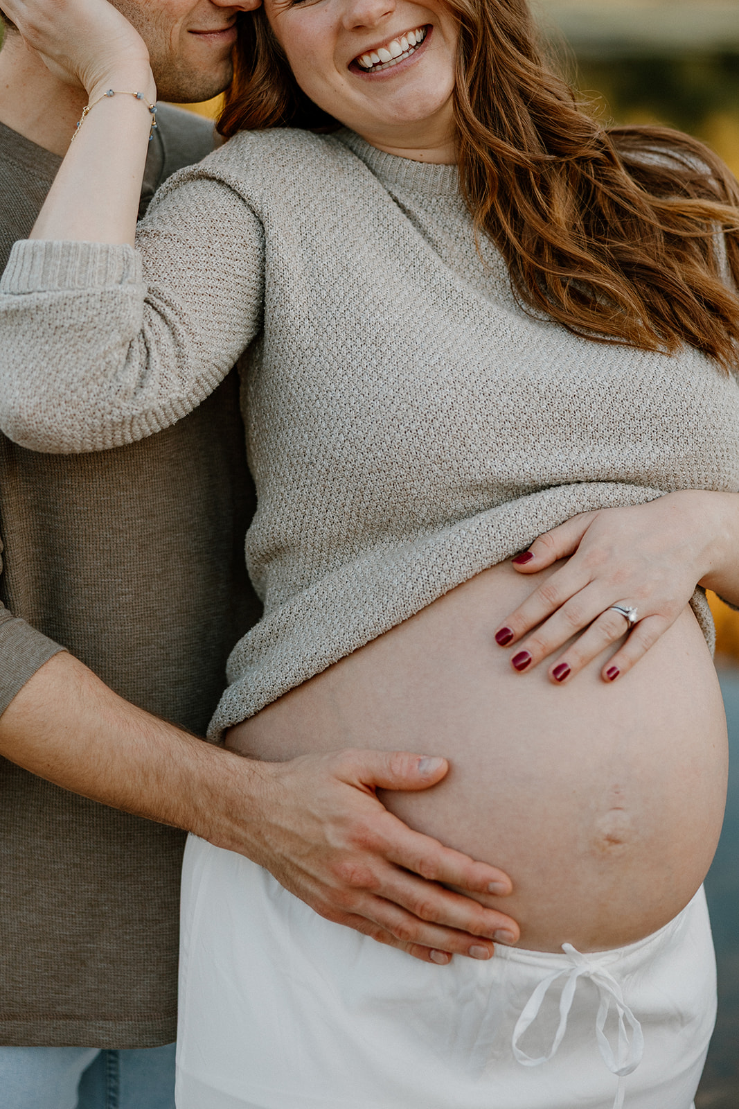Close-up of couple holding baby bump with hands gently resting on stomach
