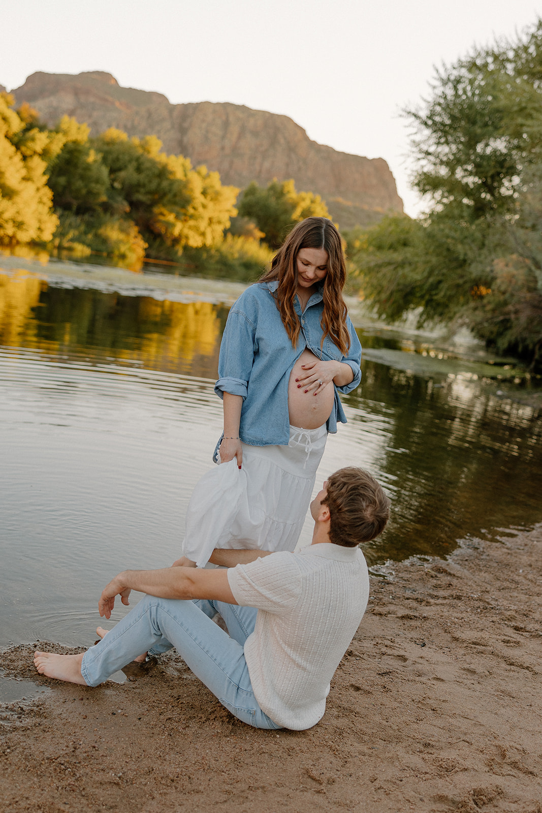 Couple sharing a quiet moment by the riverbank with soft evening light, Arizona maternity photographer
