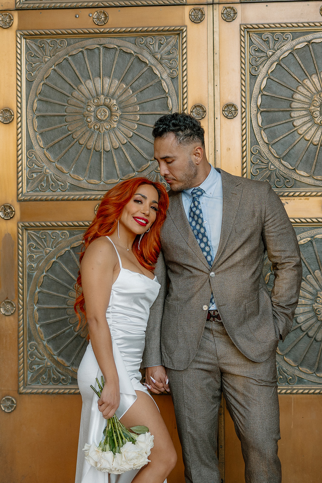 Couple standing in front of ornate gold doors during elegant phoenix engagement photos session
