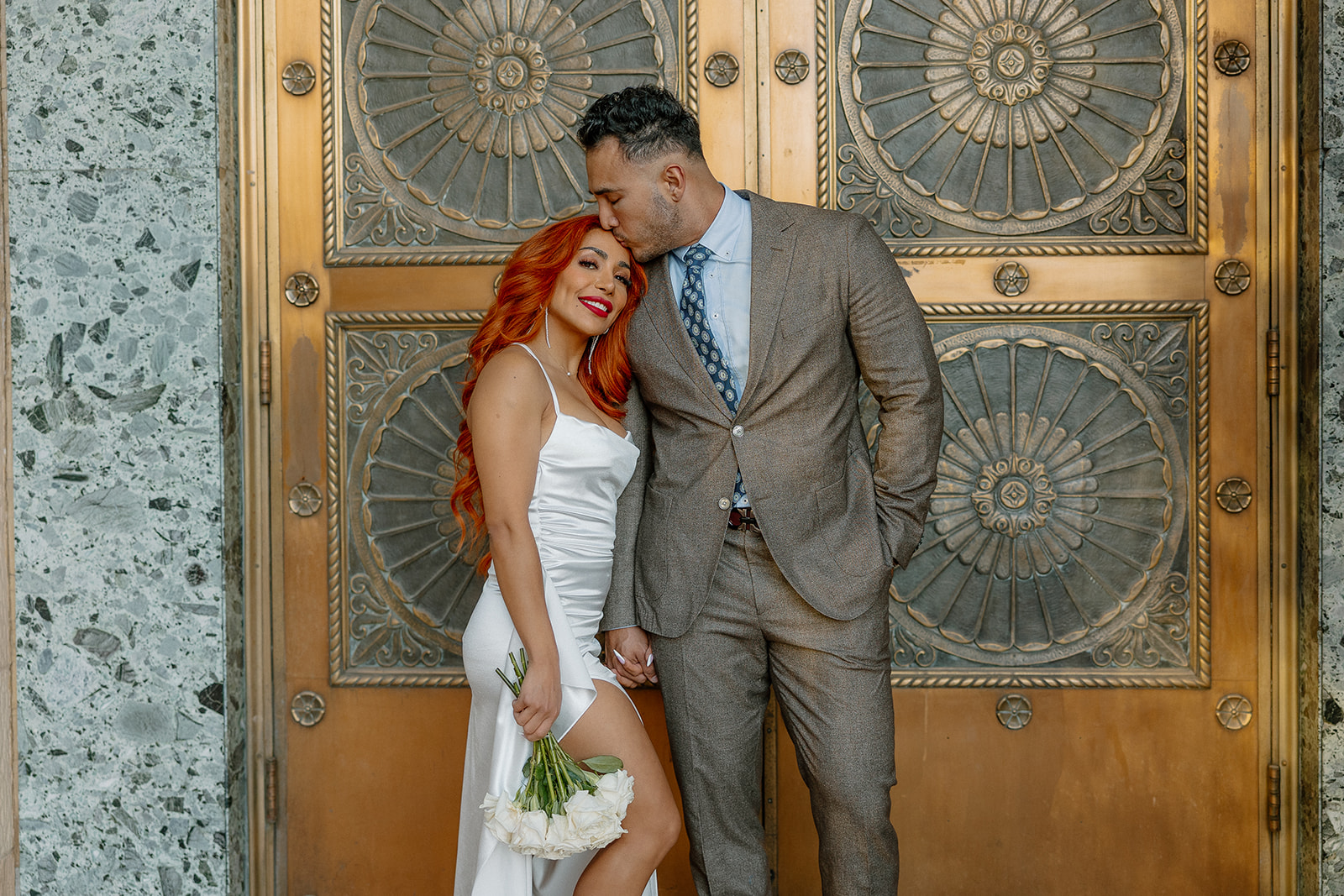 Couple standing in front of ornate gold doors during elegant downtown phoenix engagement photos
