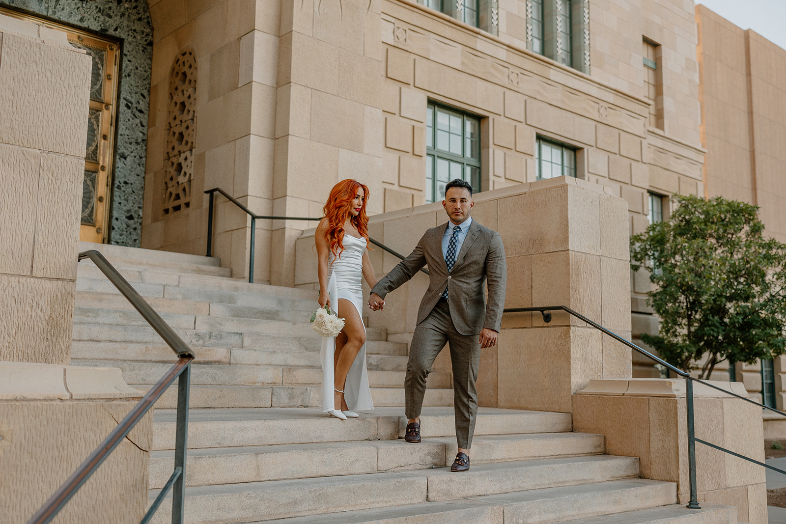 Couple walking down stone steps outside historic downtown building during engagement session
