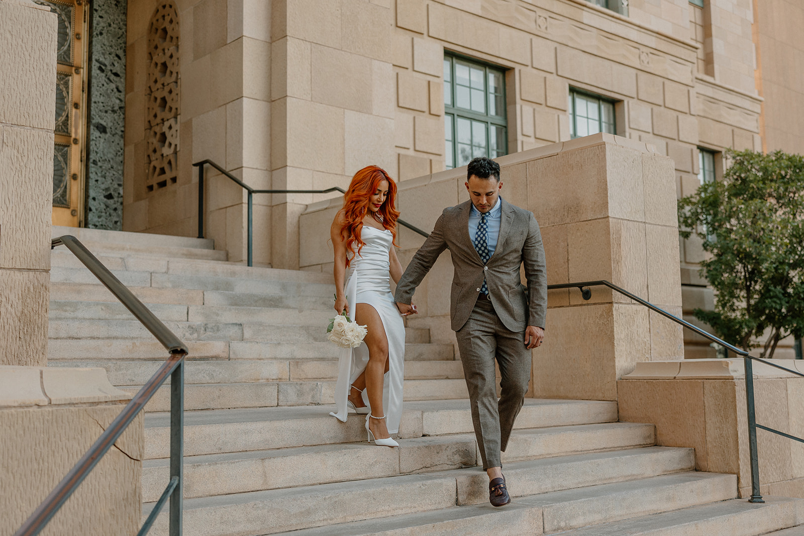 Stylish couple walking down grand stone staircase in downtown Phoenix engagement session
