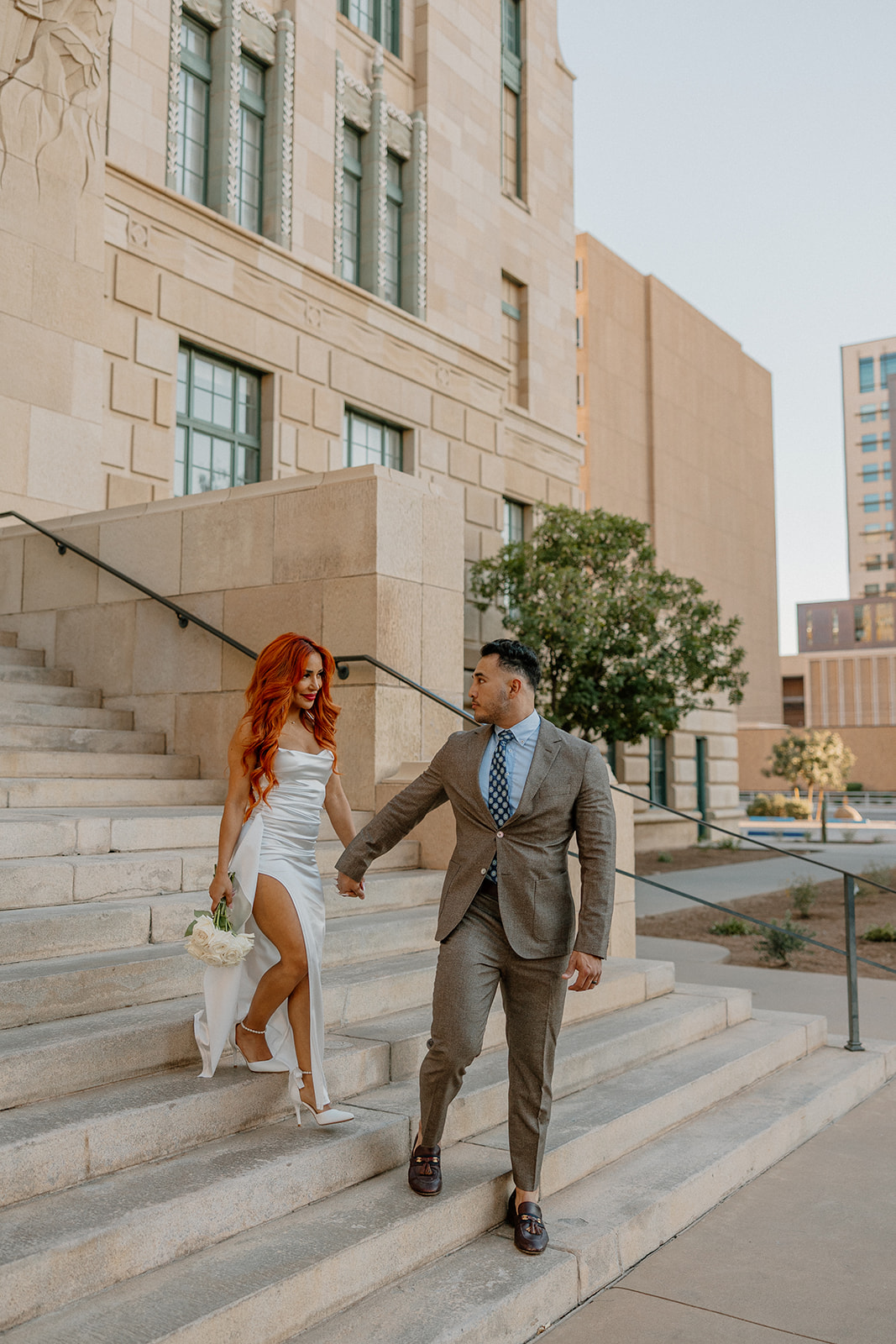 Couple walking down stone steps outside historic downtown building during phoenix engagement photos
