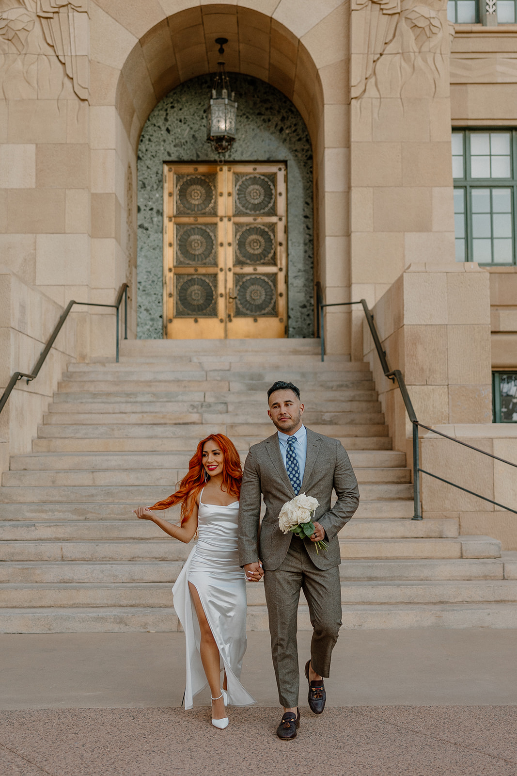 Couple walking down steps outside Phoenix City Hall during phoenix engagement photos
