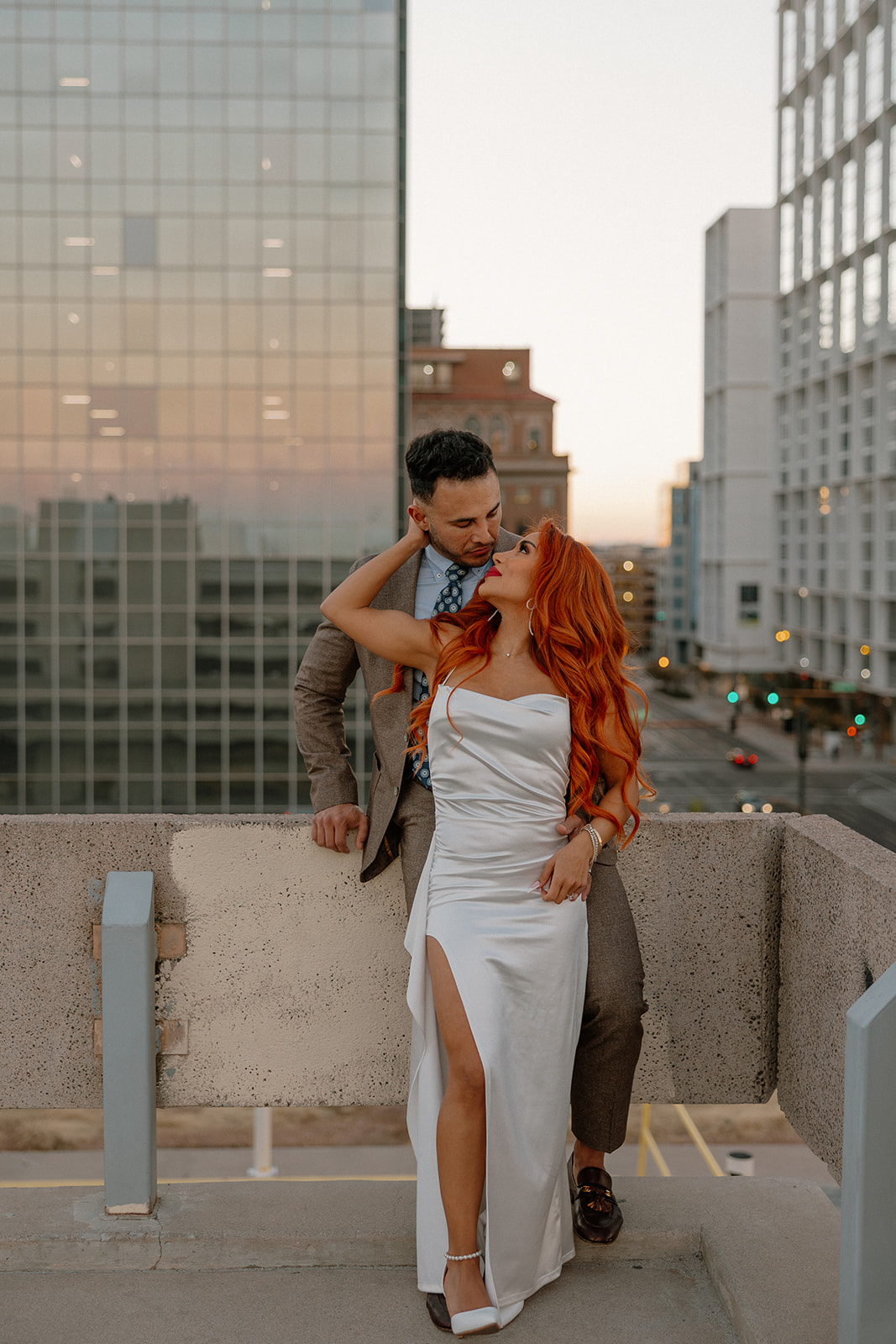 Stylish couple embracing on rooftop overlooking downtown Phoenix buildings
