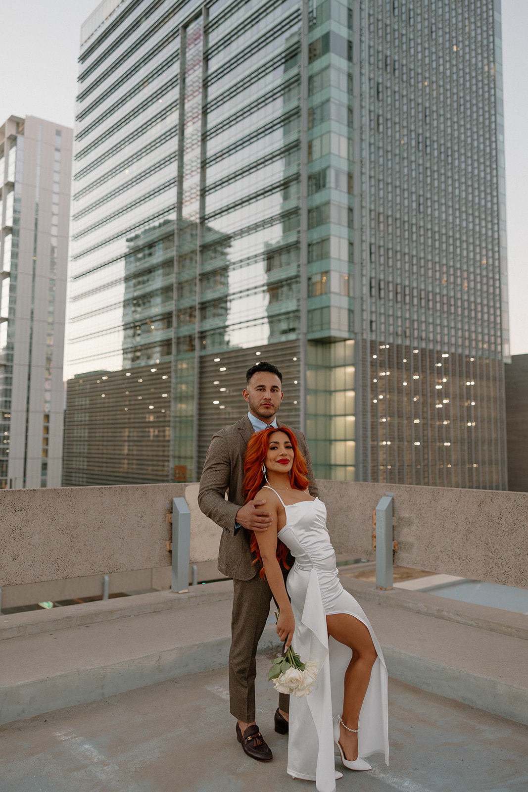 Couple posing on a downtown rooftop with Phoenix skyline during phoenix engagement photos session
