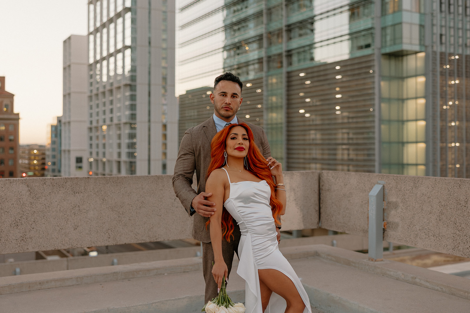 Couple posing on rooftop with downtown skyline during phoenix engagement photos
