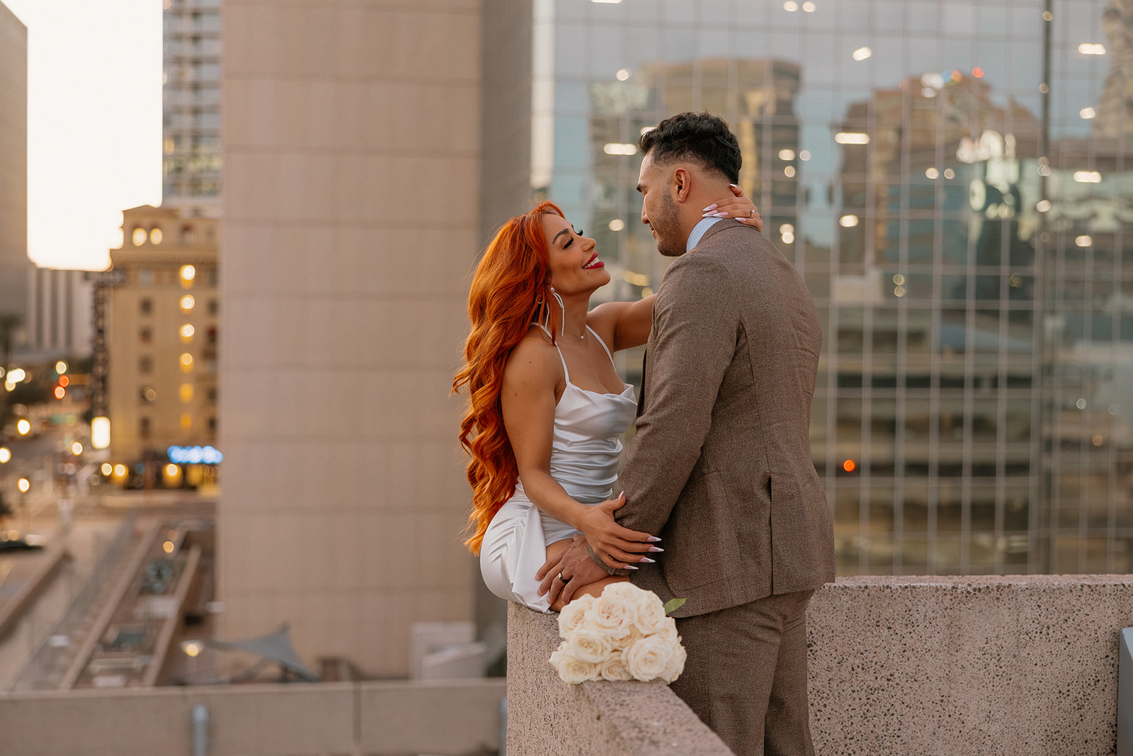 Romantic rooftop moment with city lights behind couple during downtown Phoenix engagement session

