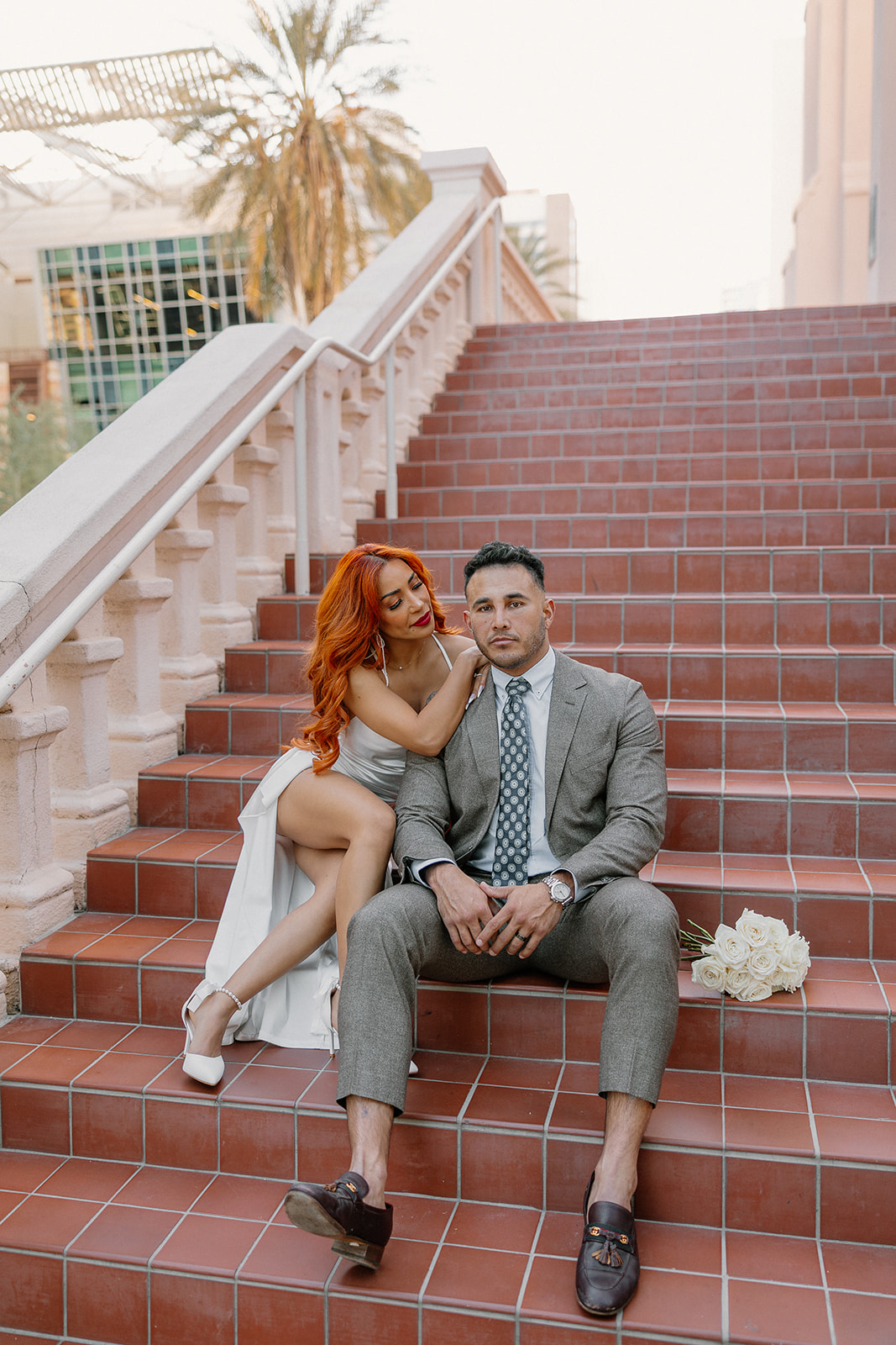 Bride leaning on groom while sitting on terracotta staircase in downtown Phoenix
