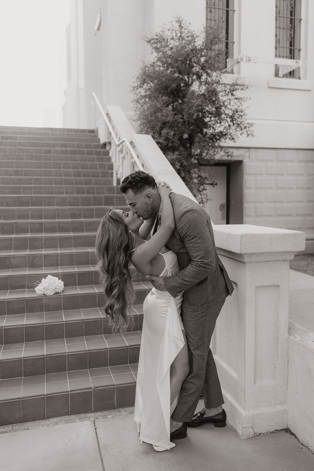 Black and white photo of couple kissing near staircase during phoenix engagement photos
