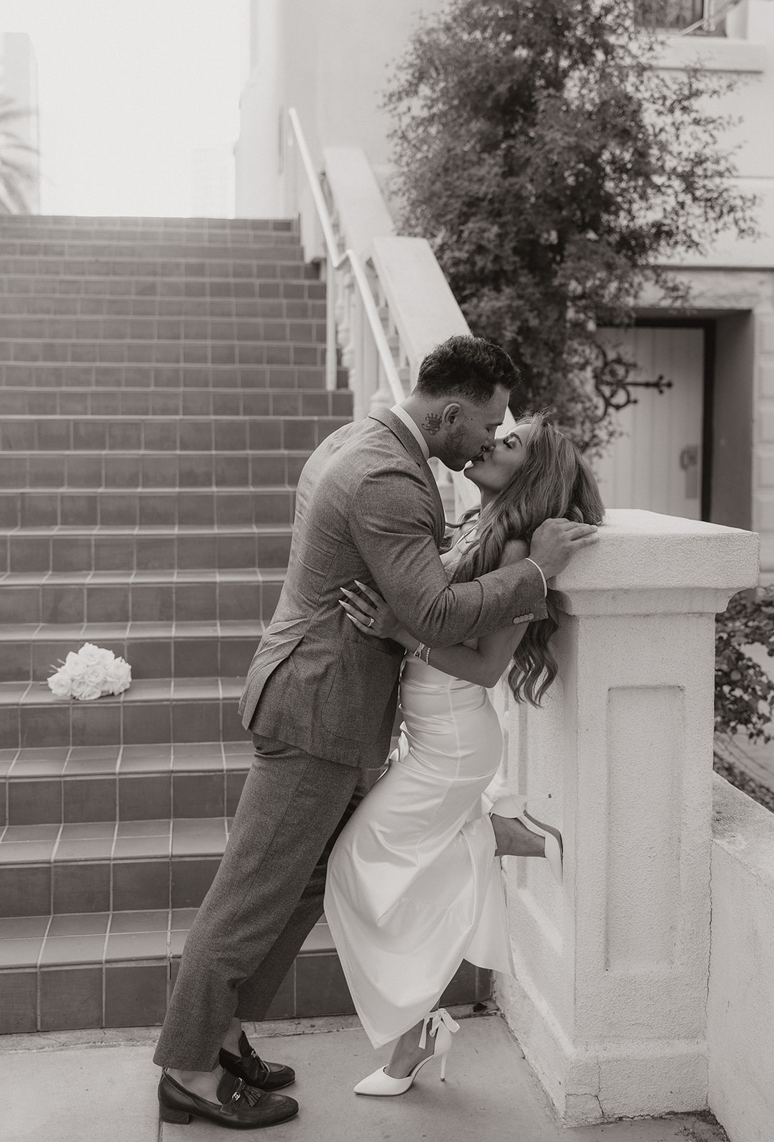 Romantic black and white moment of couple kissing beside terracotta staircase during phoenix engagement photos
