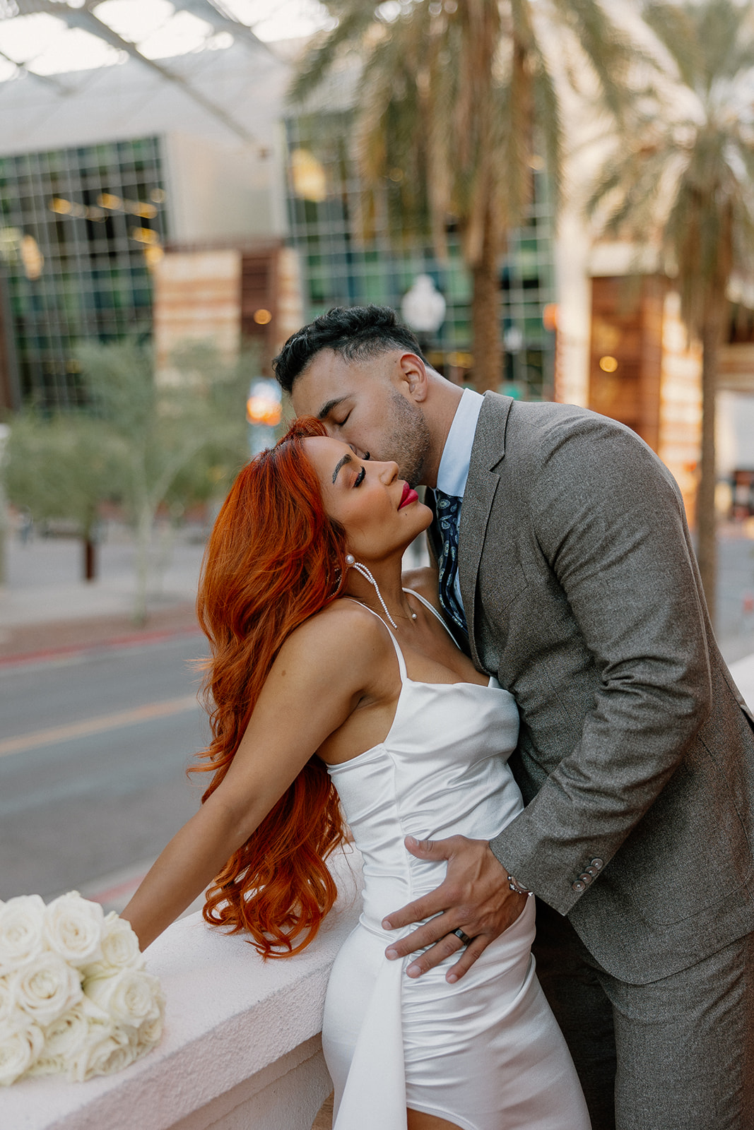 Couple embracing on palm-lined downtown street during relaxed engagement session
