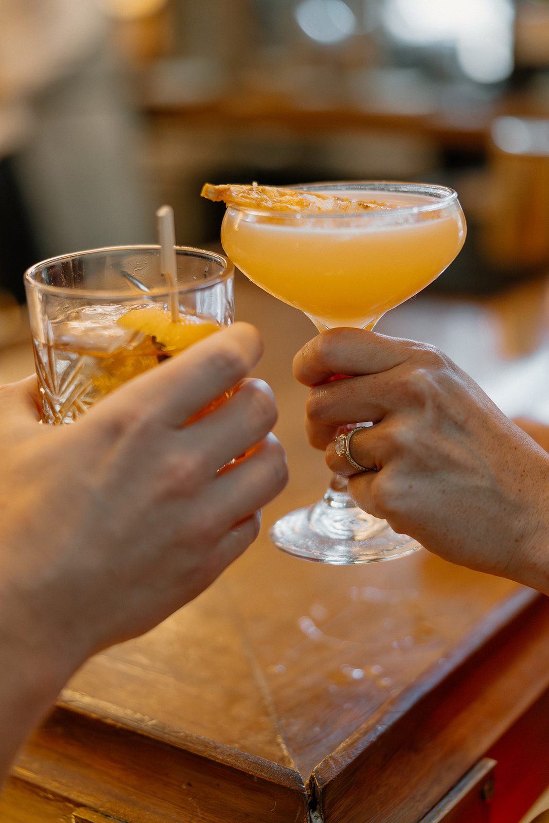 Close-up of cocktails clinking during a date-night style engagement session
