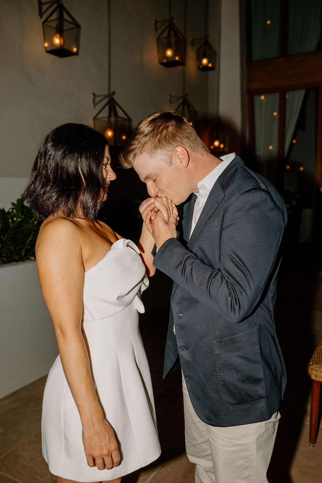 Couple sharing a quiet moment with a kiss in a softly lit hotel space
