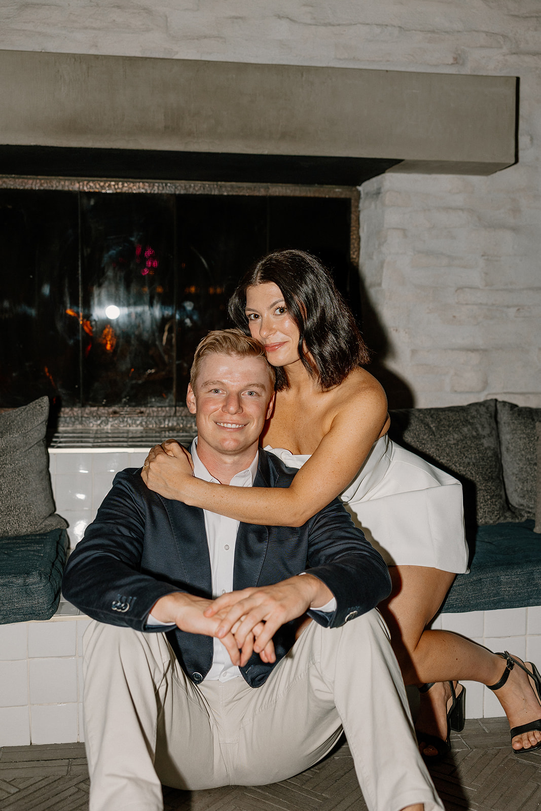 Cozy hotel engagement photos of couple sitting together by a fireplace
