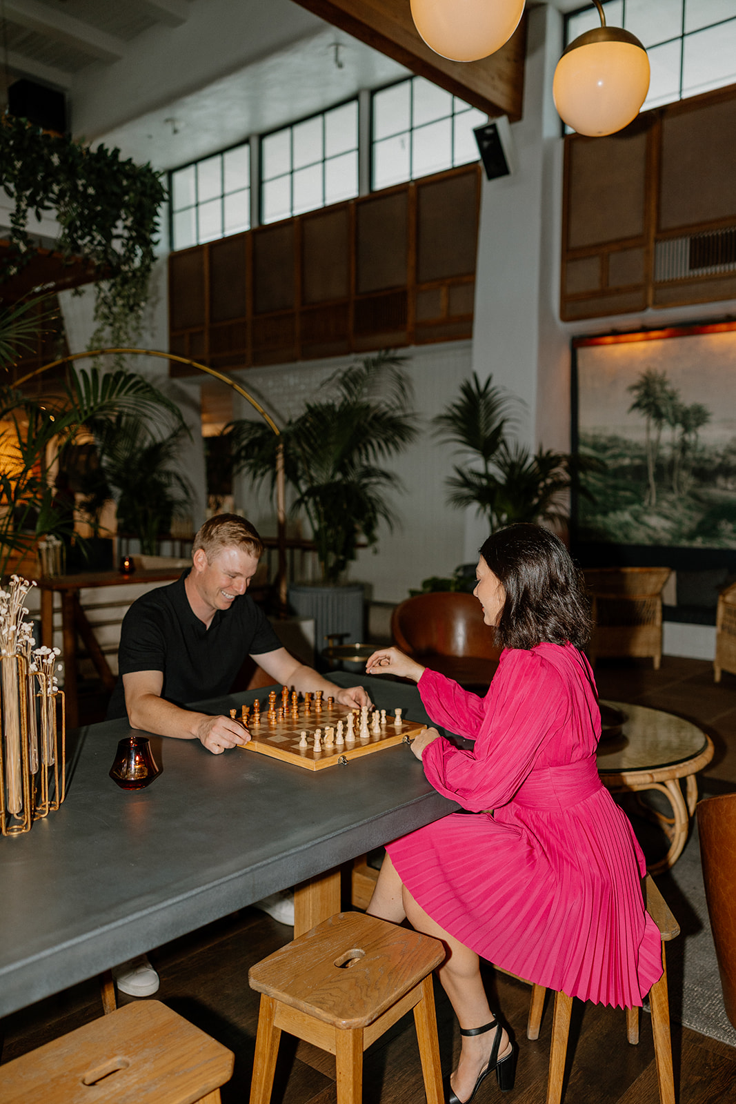 Couple playing chess together in a cozy hotel lounge during engagement session
