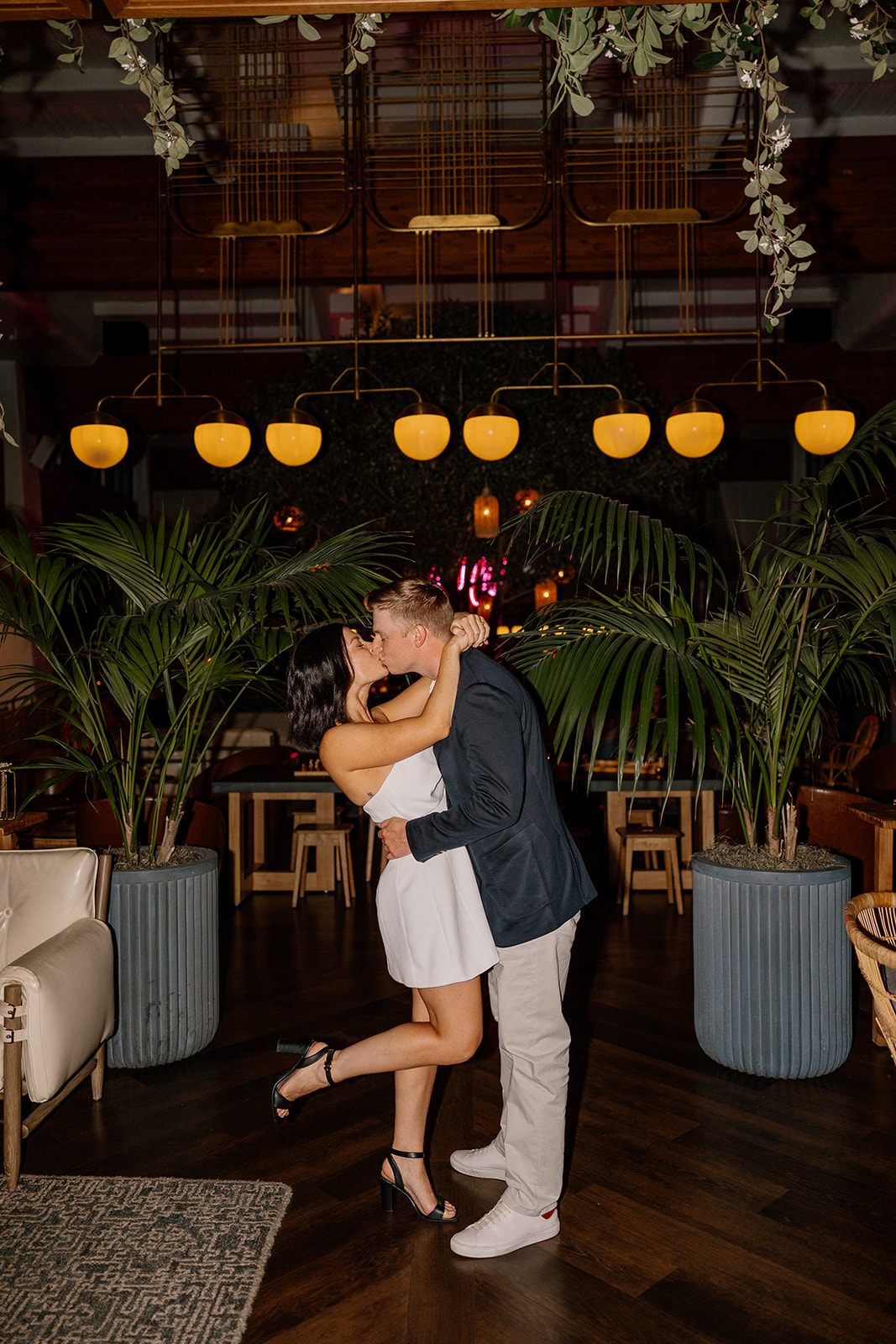 Couple kissing under warm lights in a hotel lobby at night
