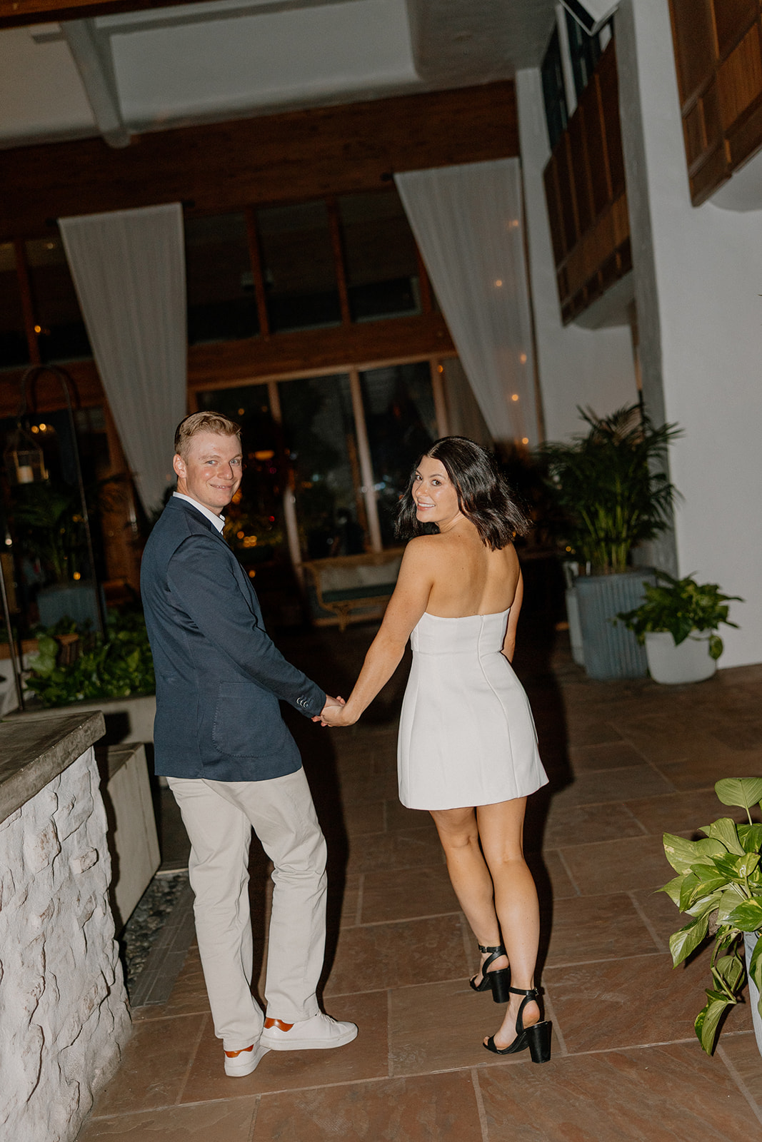Hotel engagement photos of couple walking hand in hand through a modern resort lobby
