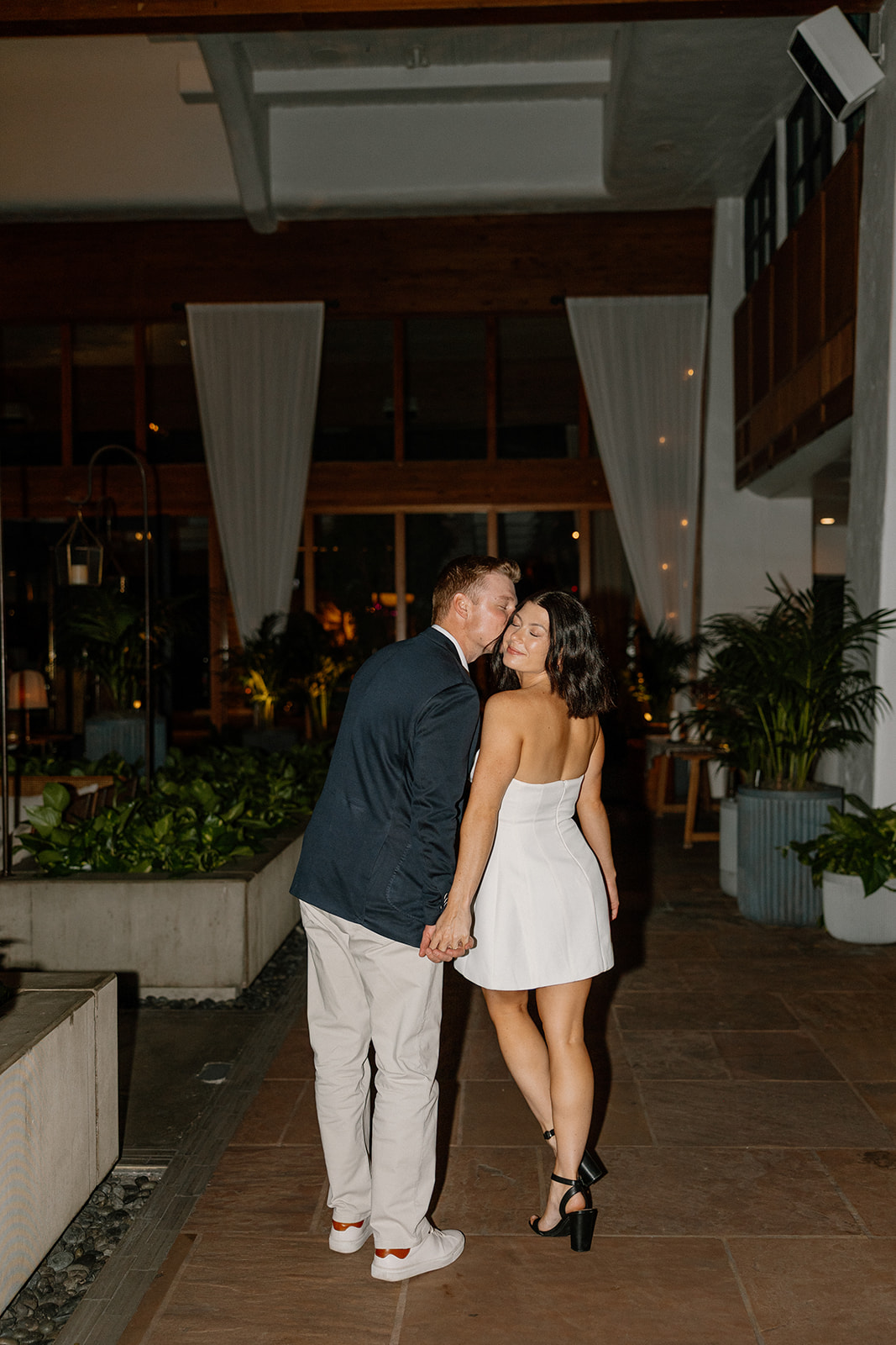 Hotel engagement photos of couple walking together in the evening with soft lighting
