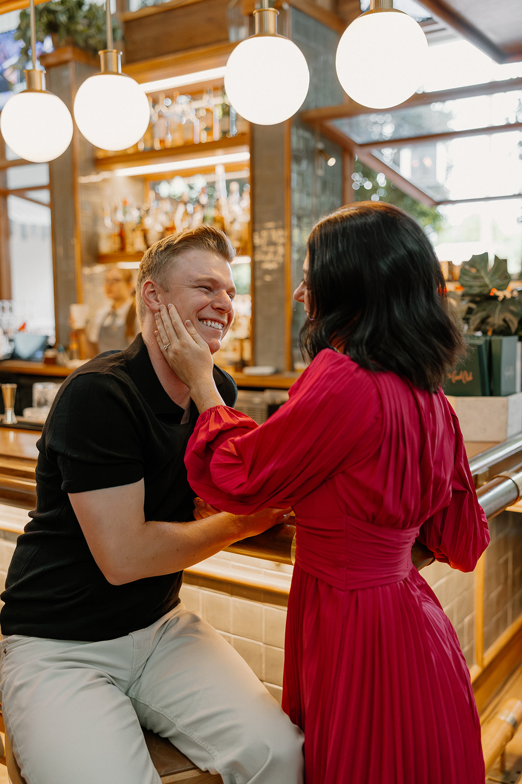 Playful hotel engagement photos at a bar with couple laughing together
