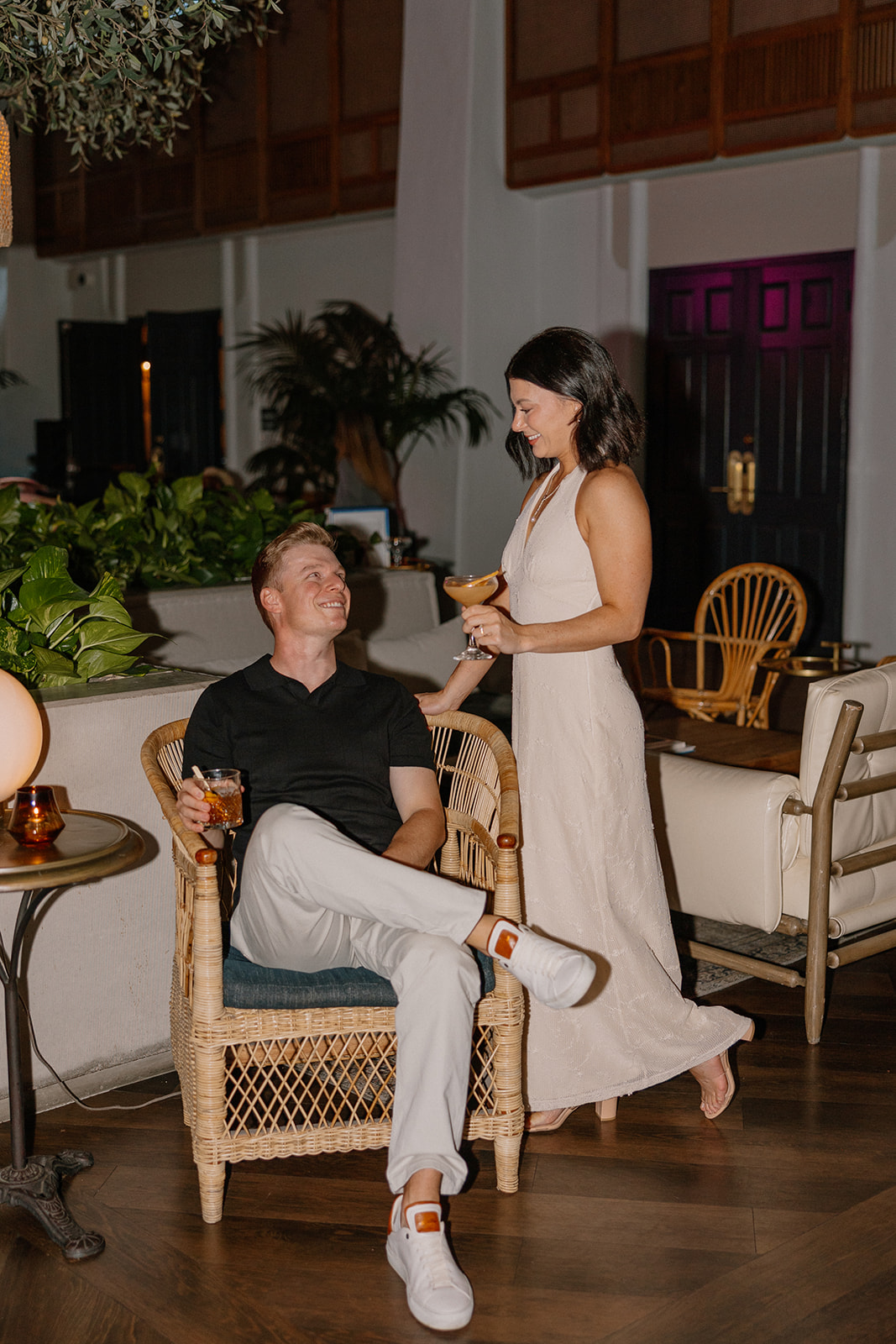 Couple relaxing with drinks in lounge seating during evening hotel engagement photos