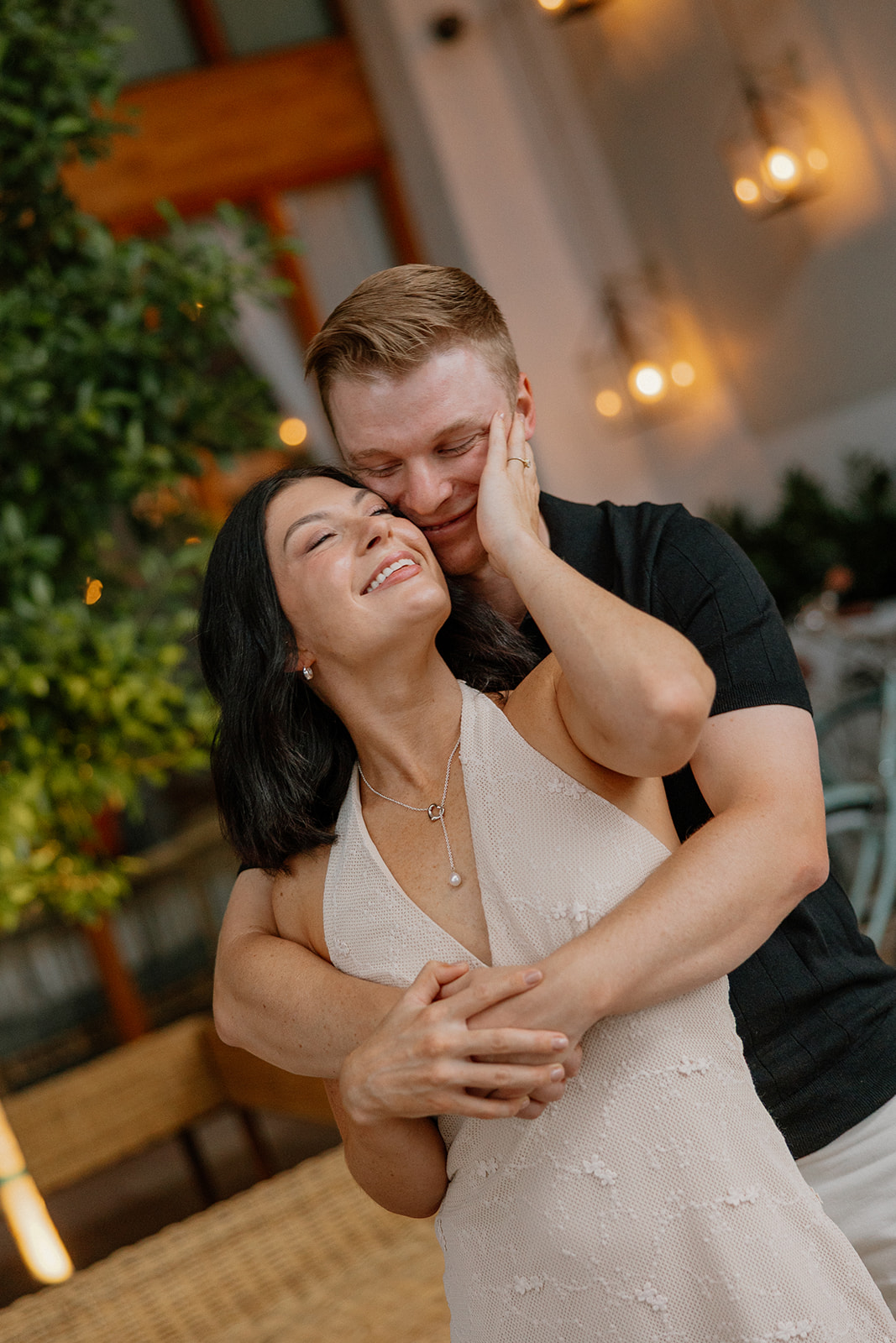Couple laughing together in a lounge chair during a relaxed evening engagement session

