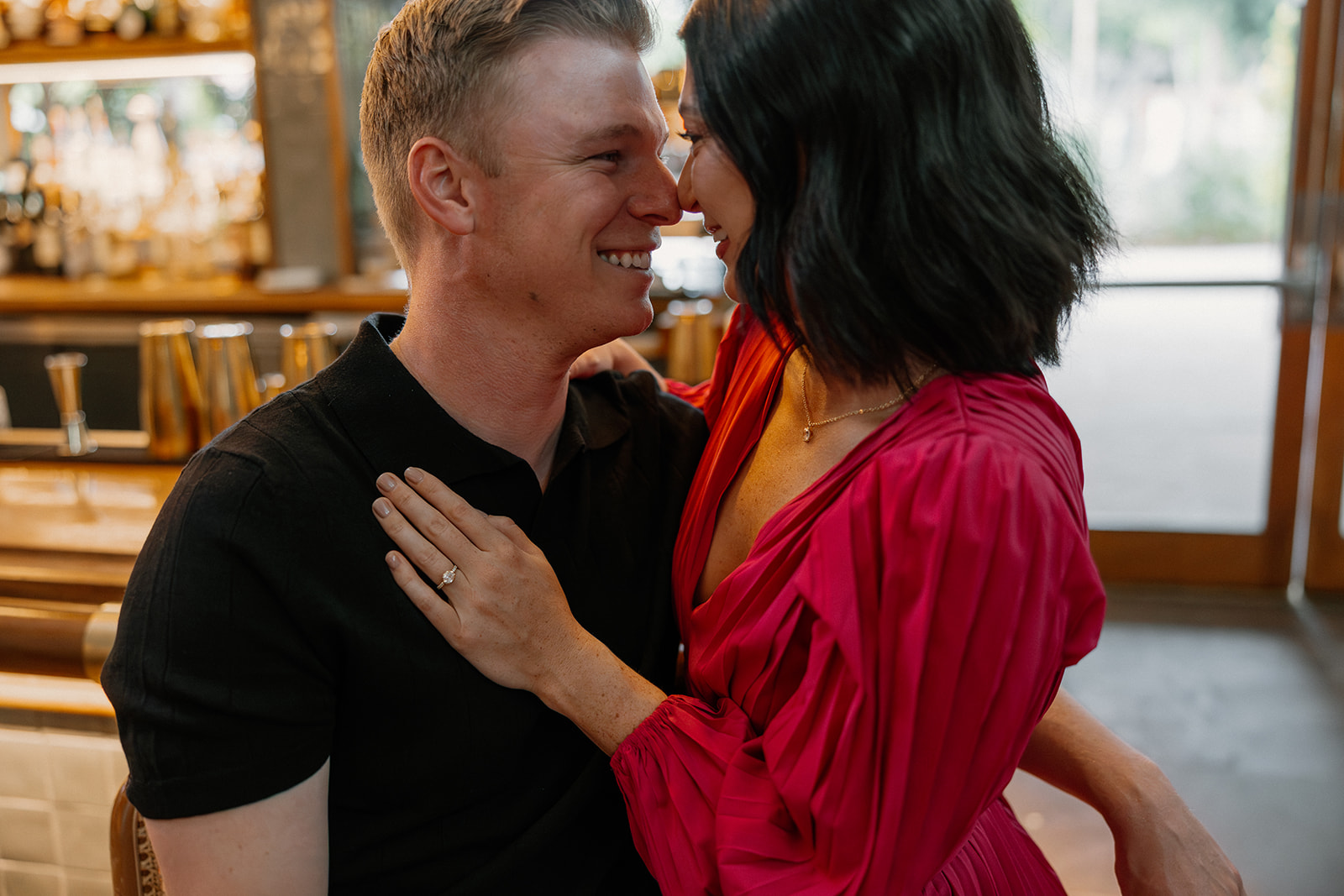 Close-up of couple smiling at each other at a hotel bar during engagement photos
