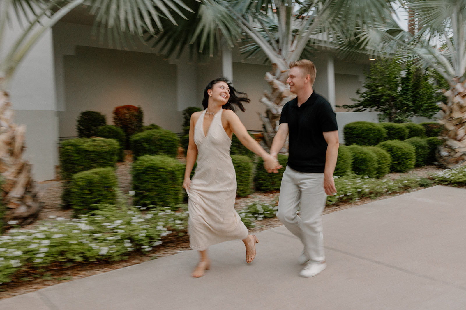 Couple running hand in hand under palm trees at a Scottsdale resort
