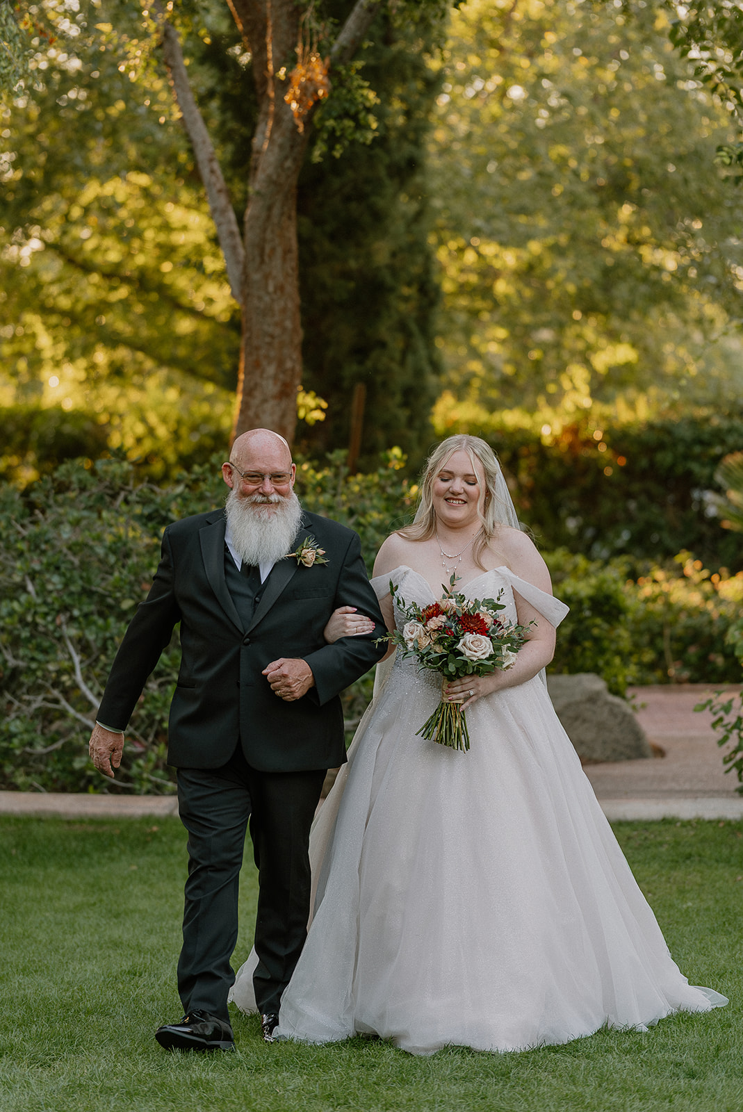 Bride walking down the aisle with her father during outdoor ceremony at Stonebridge Manor Wedding Venue