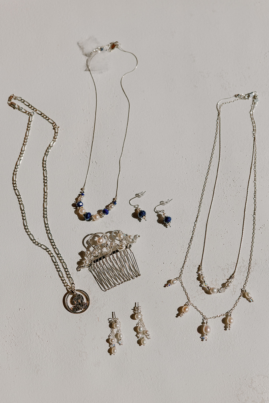 Bridal jewelry including necklace earrings and hair comb arranged for wedding day details