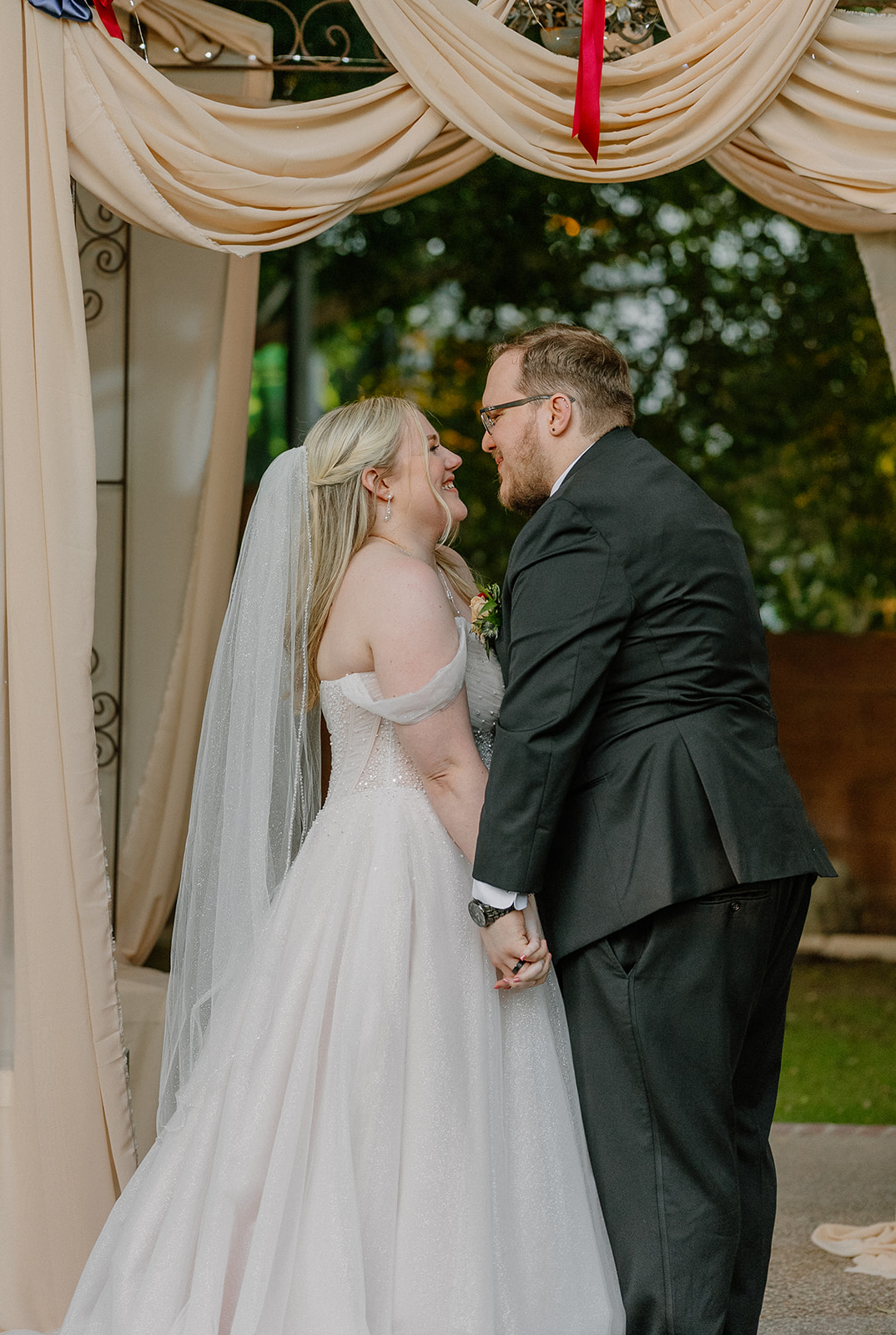 Bride and groom smiling together beneath ceremony draping at Stonebridge Manor Wedding Venue