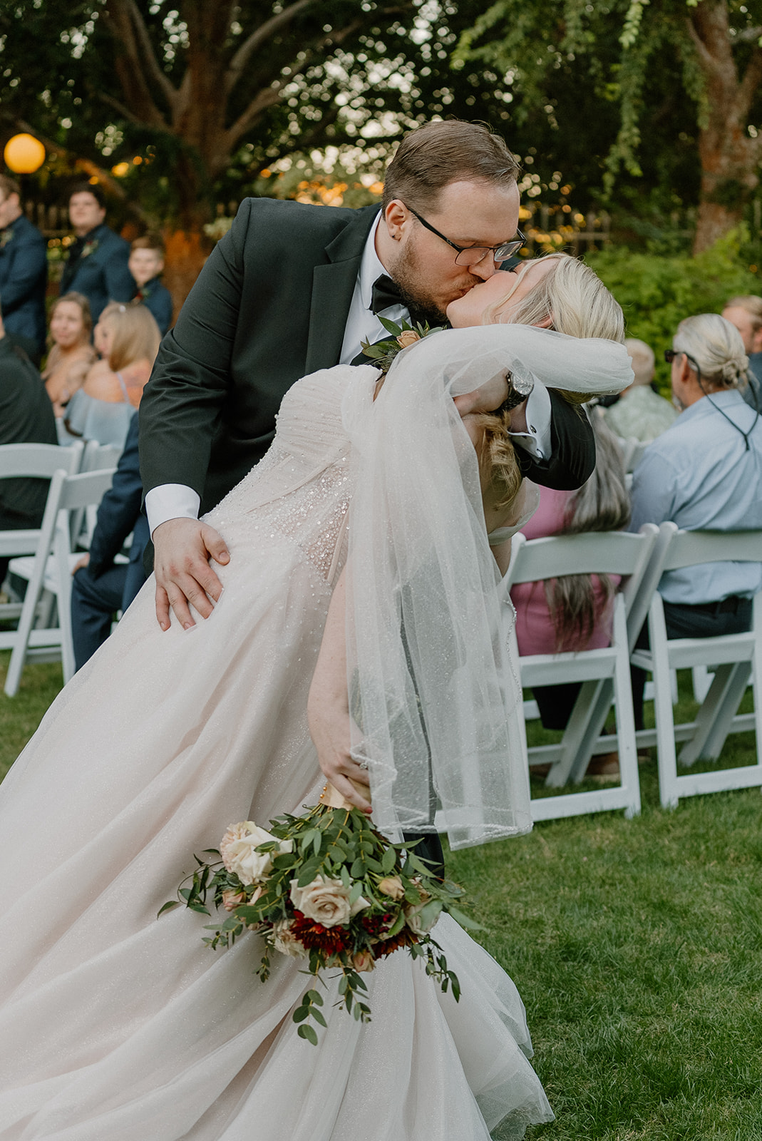 Groom dipping bride for kiss during outdoor ceremony at Stonebridge Manor Wedding Venue
