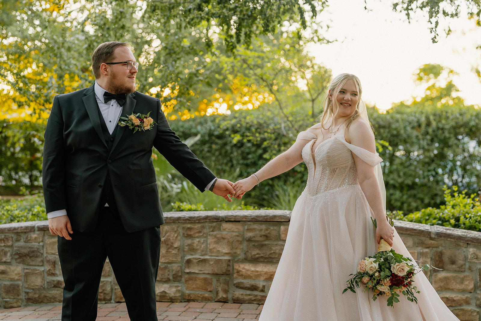 Bride and groom holding hands during sunset portraits in the Stonebridge Manor garden