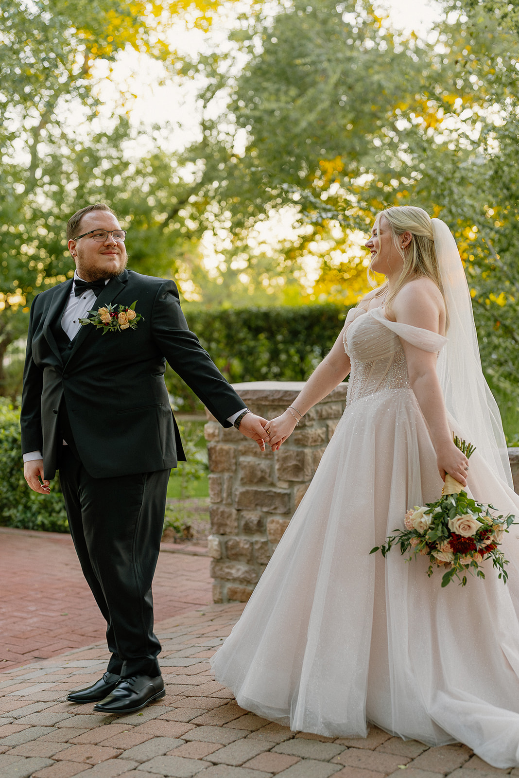 Bride and groom walking hand in hand during wedding portraits in garden