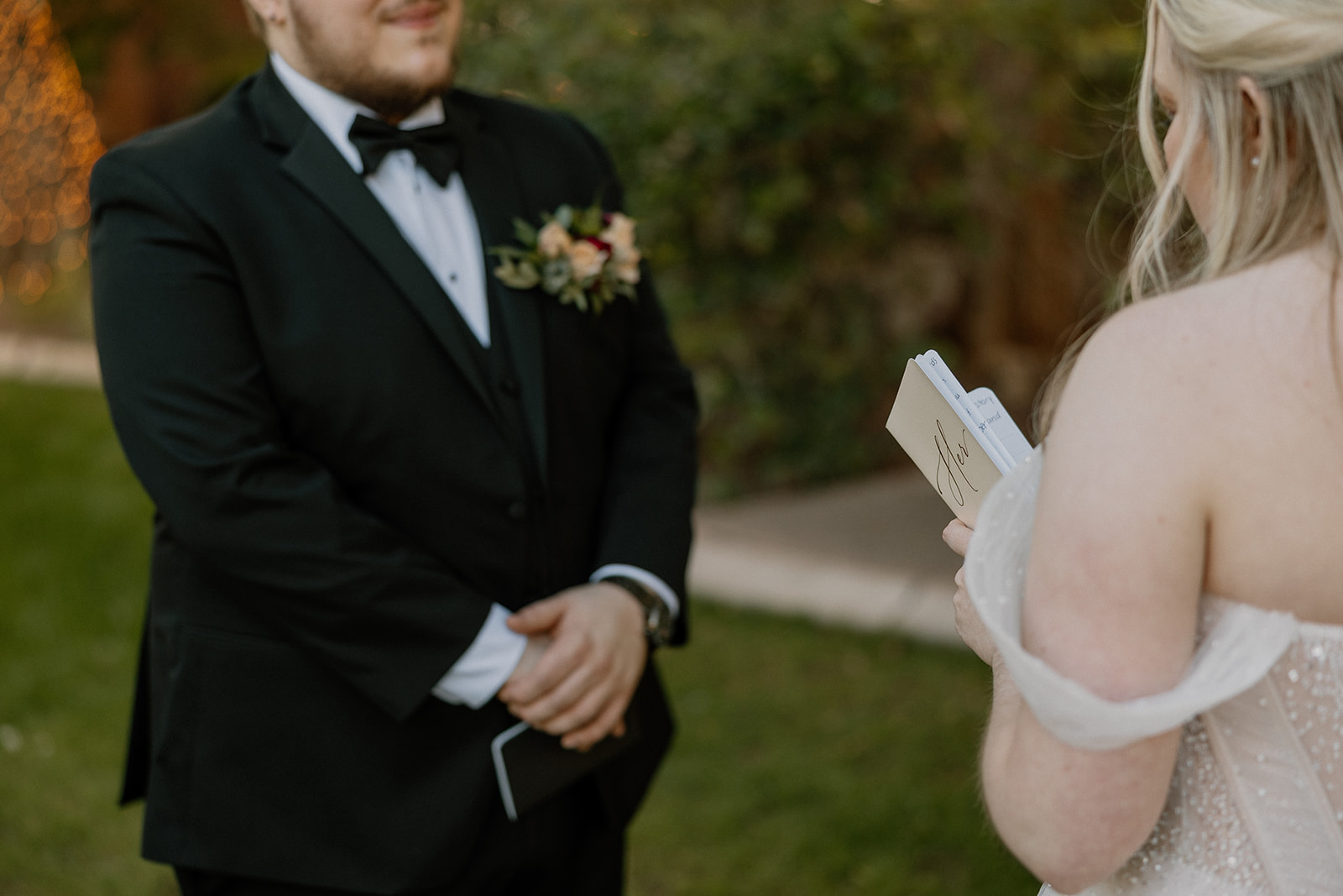 Bride reading handwritten vows to groom during intimate outdoor ceremony
