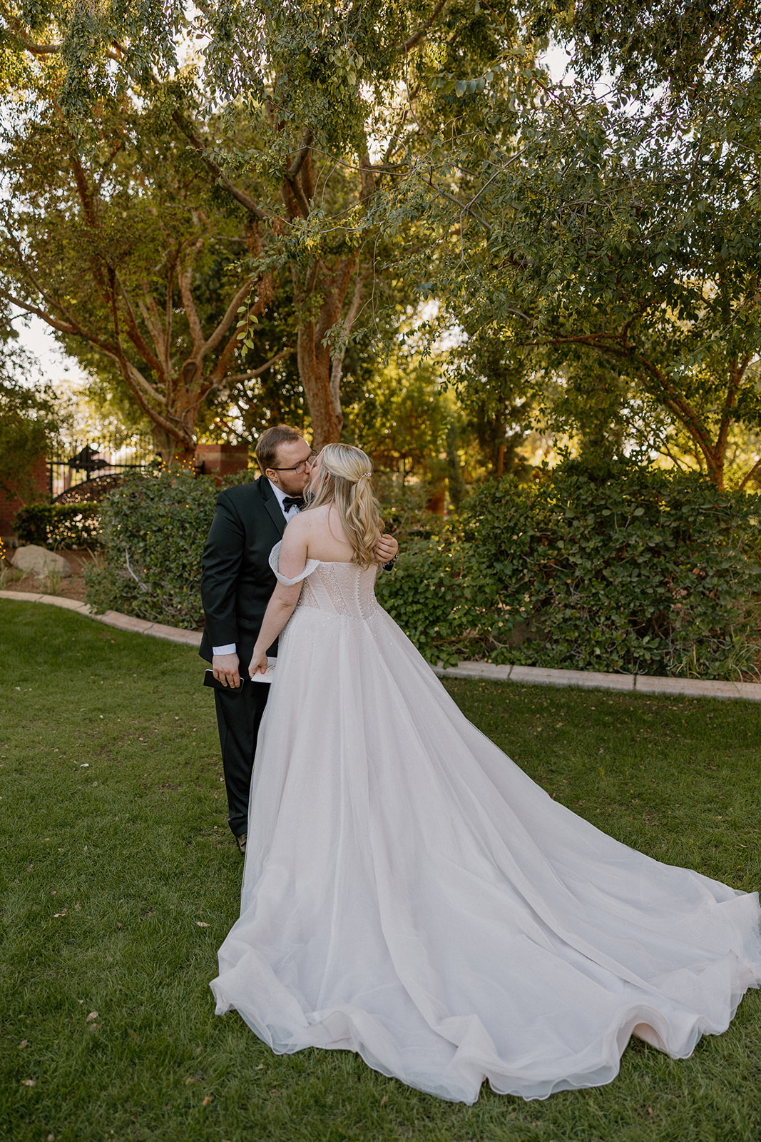 Bride and groom sharing a kiss during sunset portraits on the lawn at Stonebridge Manor Wedding Venue