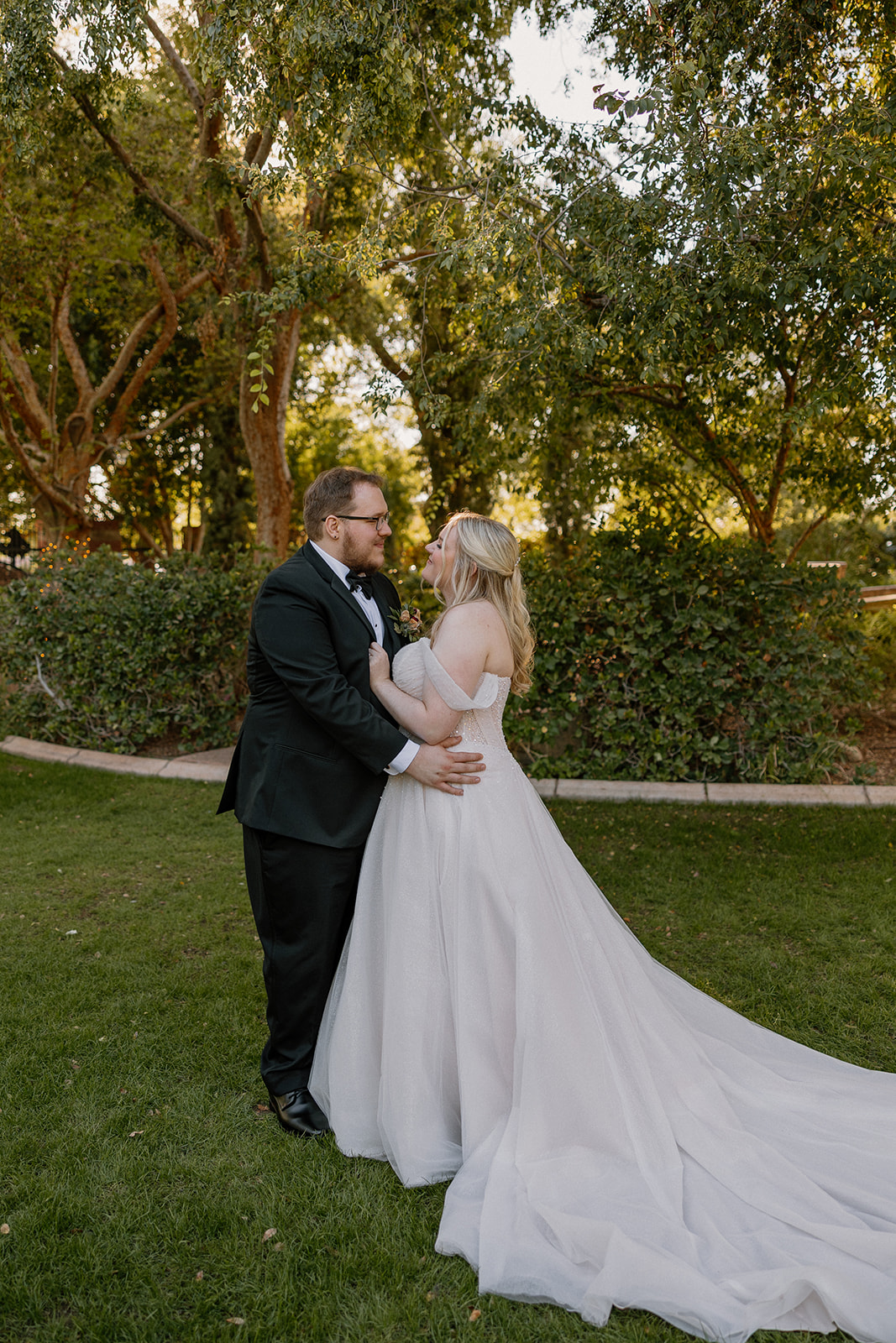 Bride and groom embracing on green lawn during portraits at Stonebridge Manor Wedding Venue