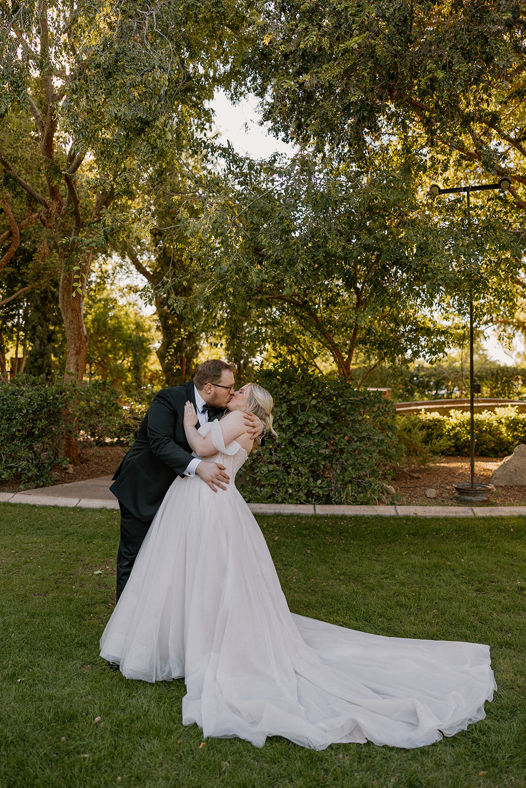 Bride and groom kissing during sunset portraits on the lawn at Stonebridge Manor Wedding Venue